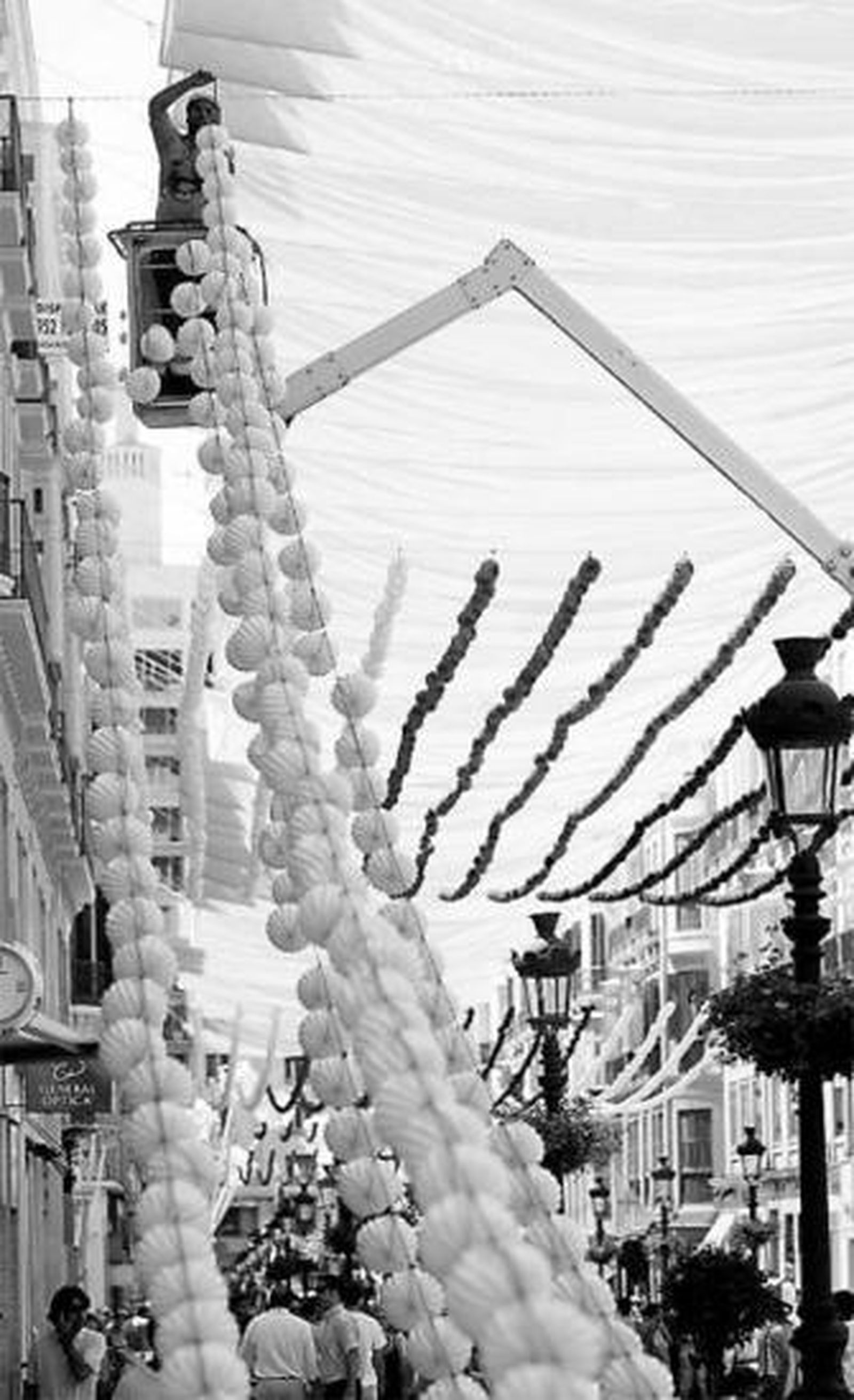 Un operario coloca farolillos en la calle Larios.