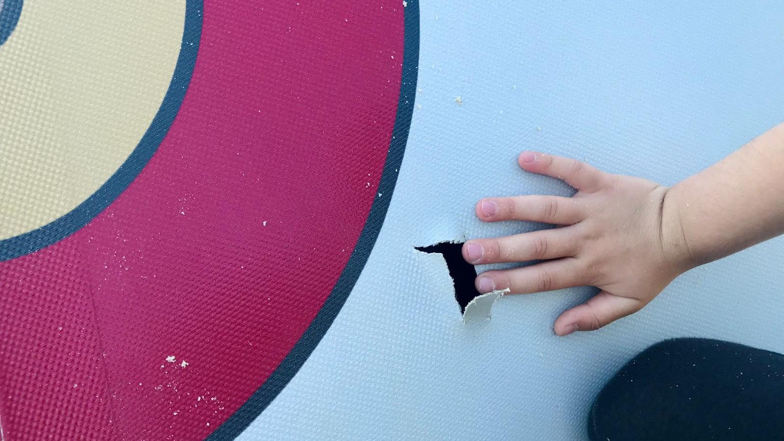 Una niña apunta hacia un nuevo sabotaje en el trampolín pequeño: un orificio deja escapar el aire.