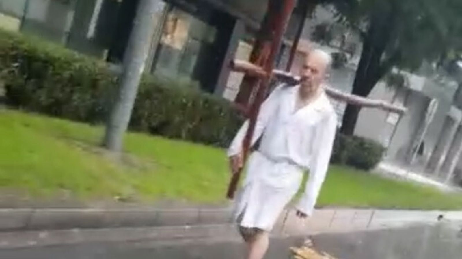 El hombre con la cruz bajo la lluvia.