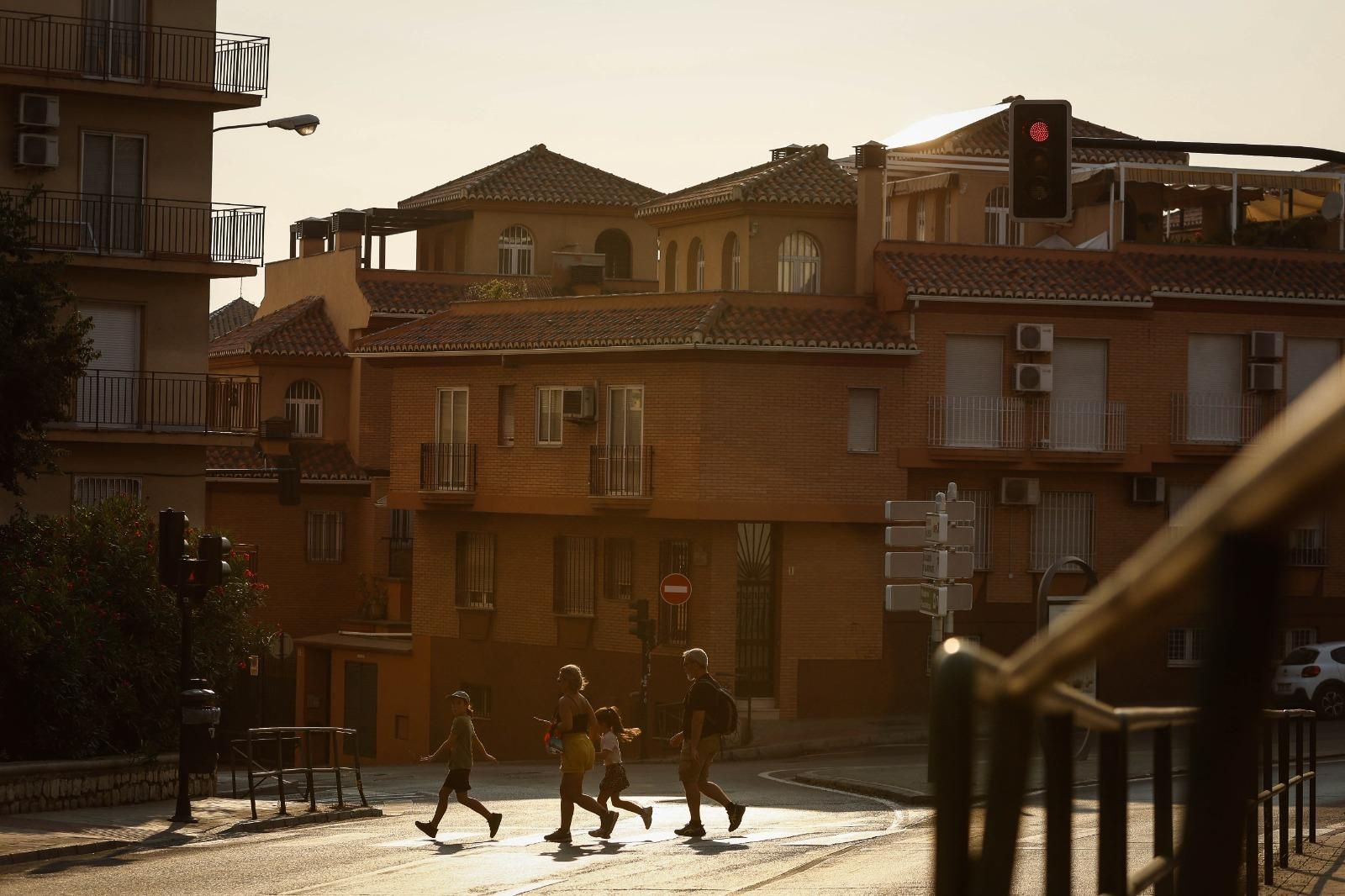 Una familia cruza un paso de peatones bajo un cielo con tonos grises y marrones