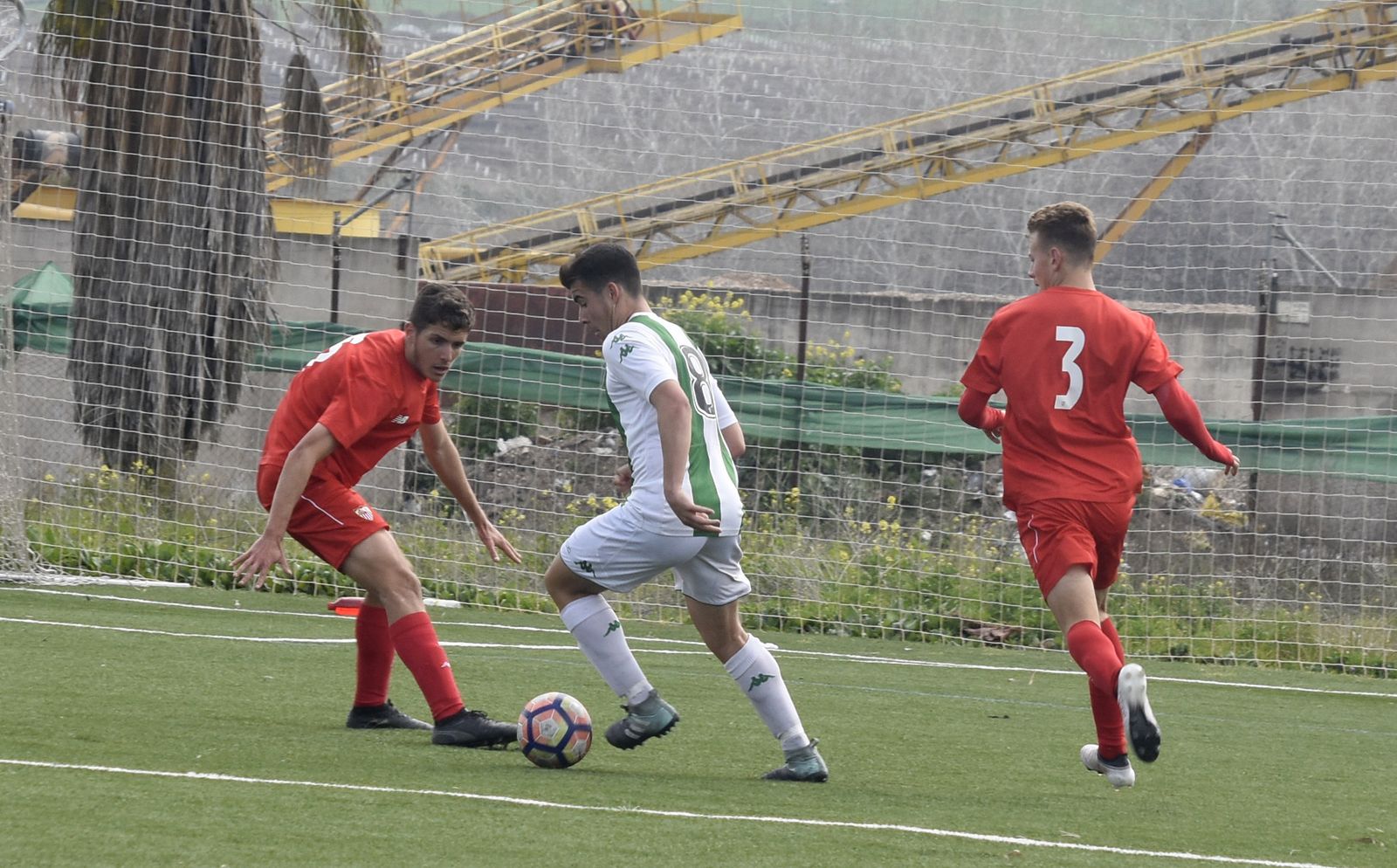 Un jugador blanquiverde trata de driblar a uno del Sevilla.