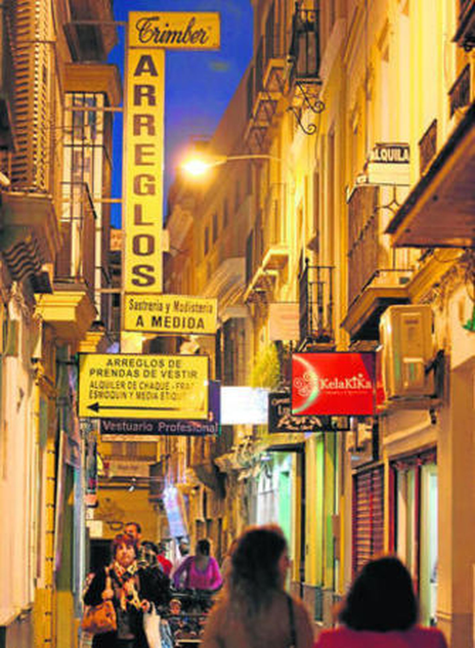Peatones por la céntrica José Gestoso, calle repleta de rótulos en banderolas.