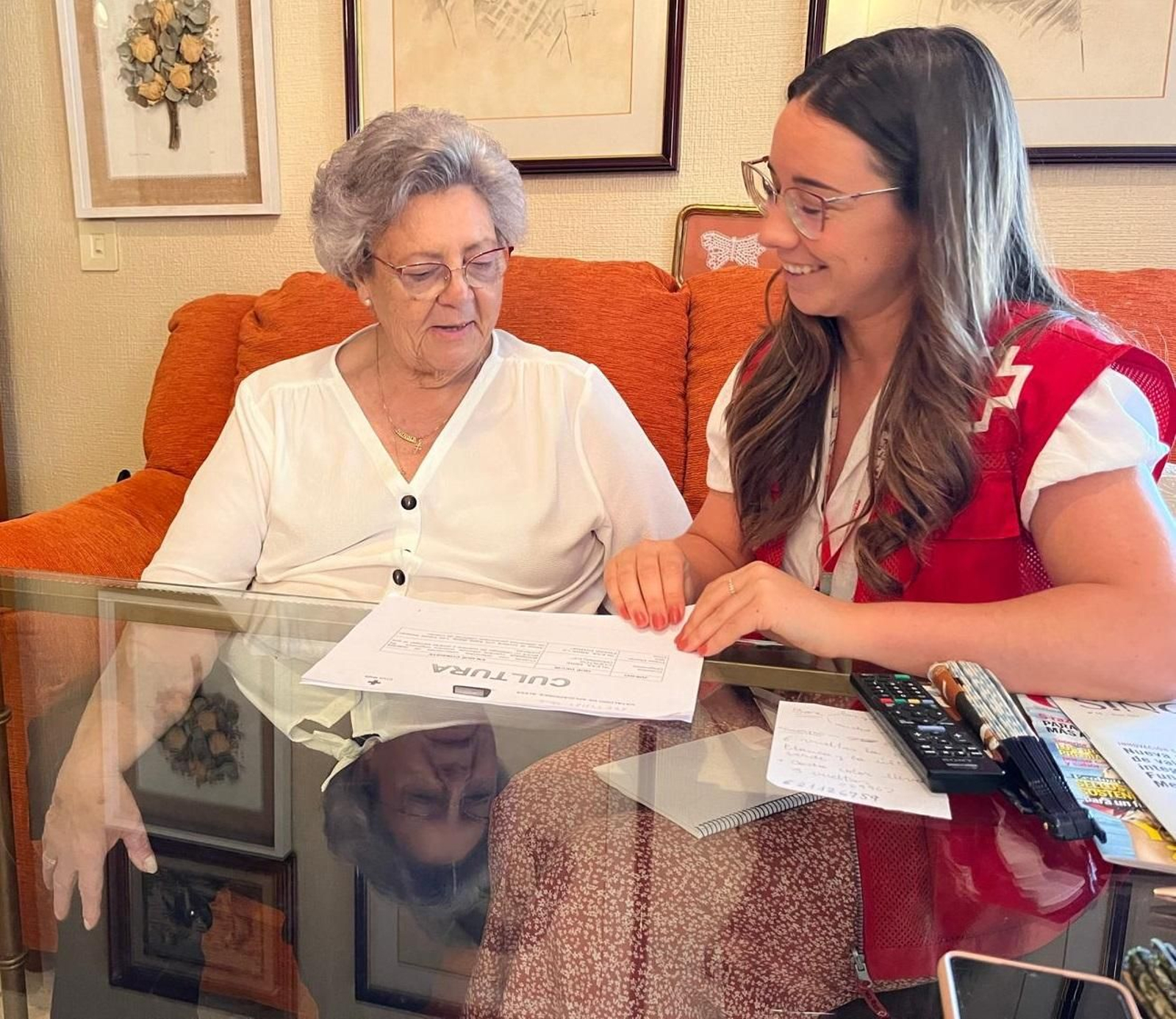 Una voluntaria de Cruz Roja, junto a una mujer mayor en su casa.