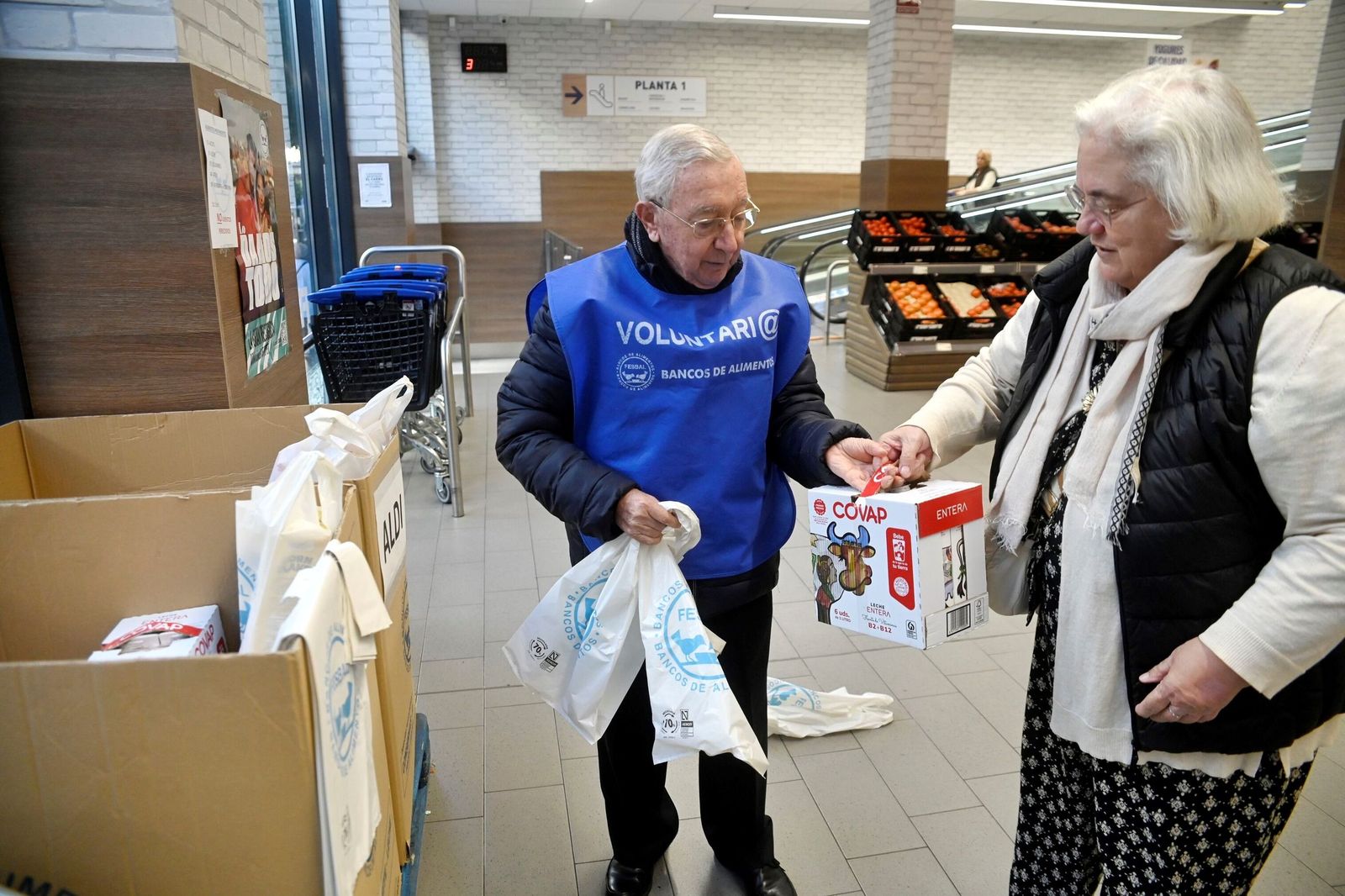 Una mujer doña un pack de cajas de leche durante la Gran Recogida