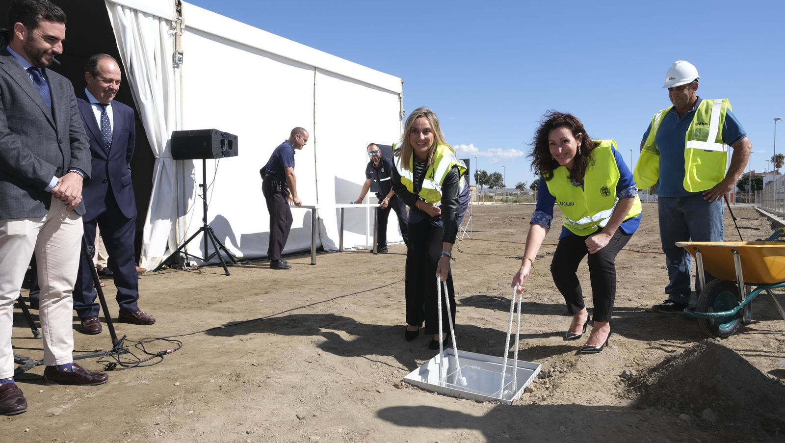 La consejera y la alcaldesa introducen la urna con los periódicos del día como primera piedra