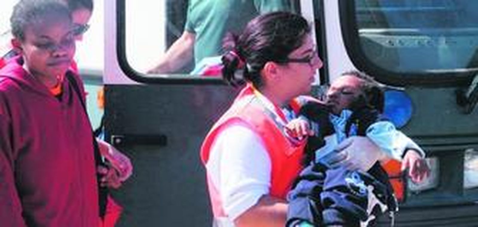 Una voluntaria de Cruz Roja lleva en brazos a un pequeño, dormido, tras llegar a Tarifa.