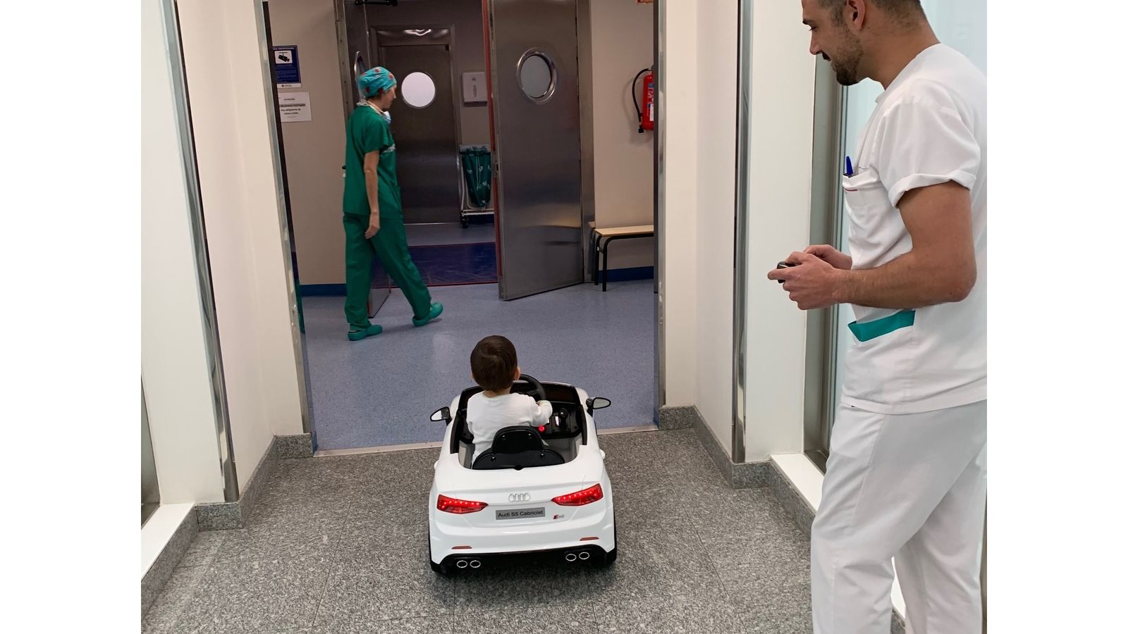 Niño en el cochecito eléctrico se dirige a los quirófanos en el Vithas Nisa de Bormujos.
