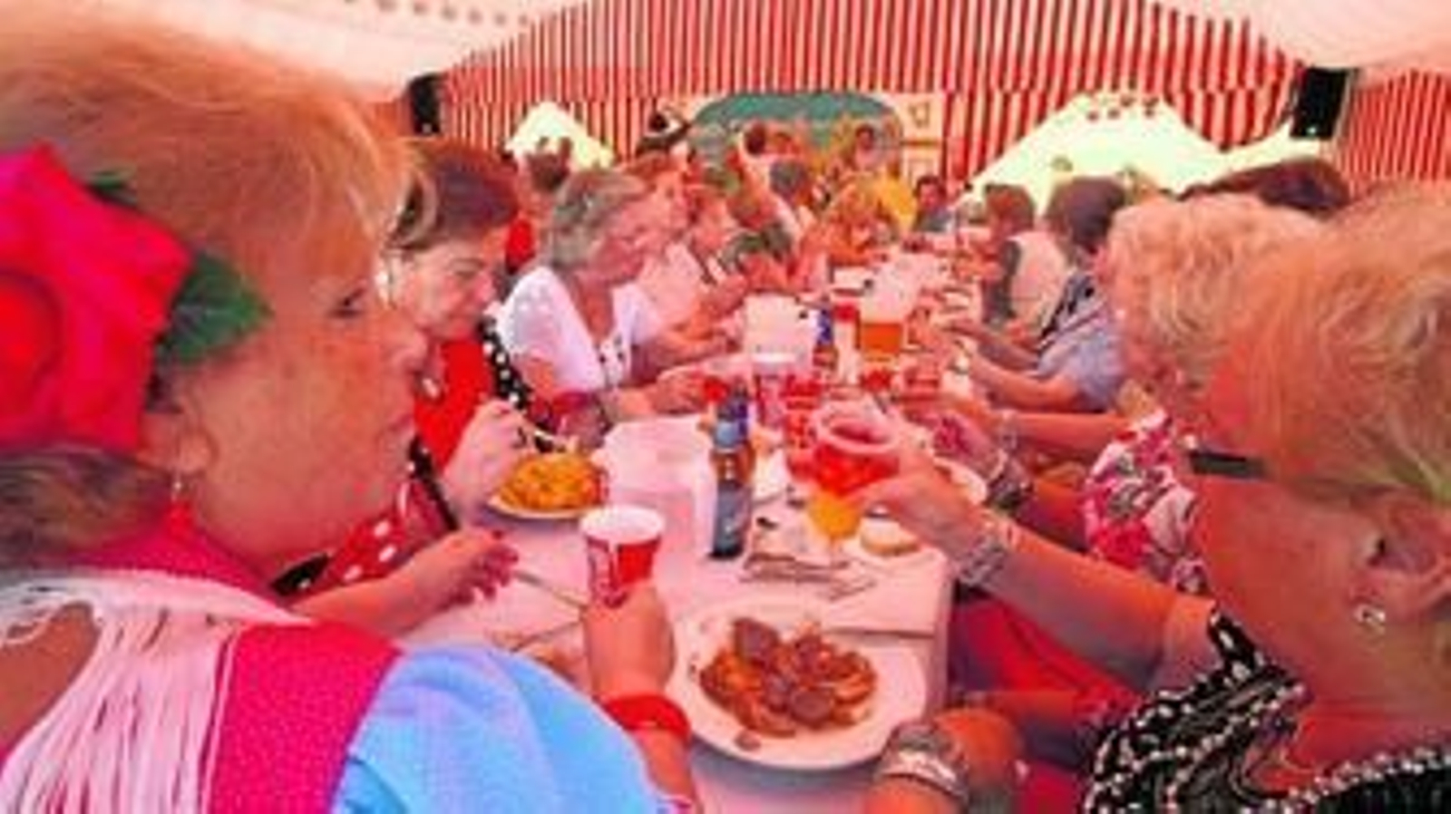 Un grupo de mujeres almuerza en una de las seis casetas de distritos con la que cuenta el real.