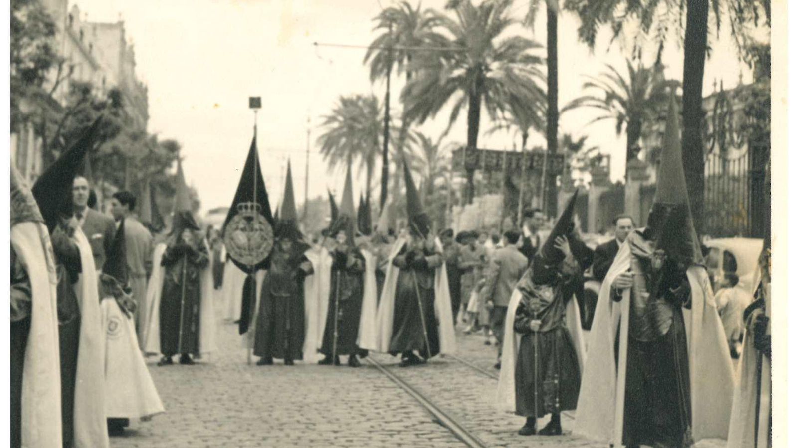 Nazarenos de las Cigarreras en la calle San Fernando, con el palio saliendo de la Universidad.