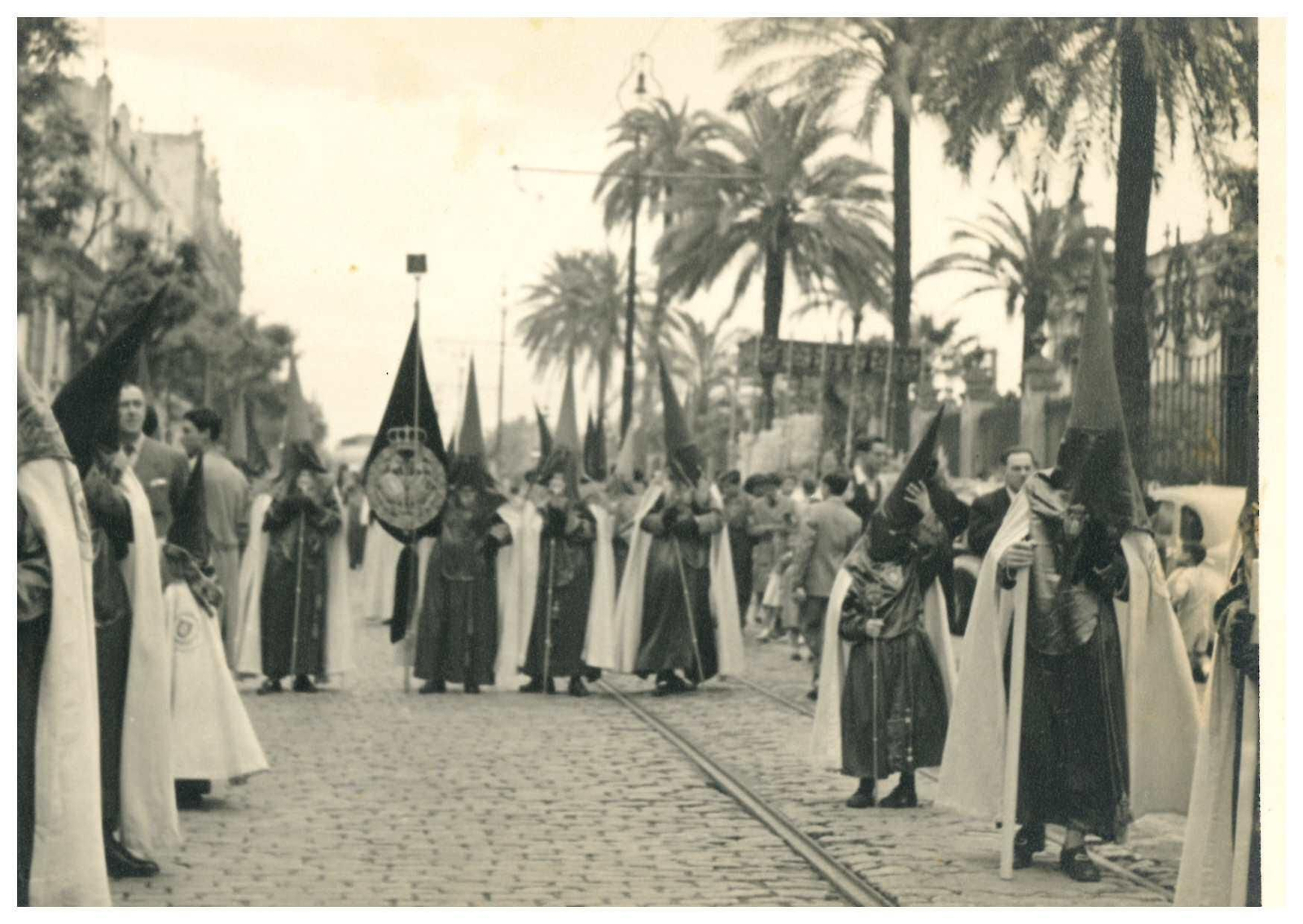 Nazarenos de las Cigarreras en la calle San Fernando, con el palio saliendo de la Universidad.