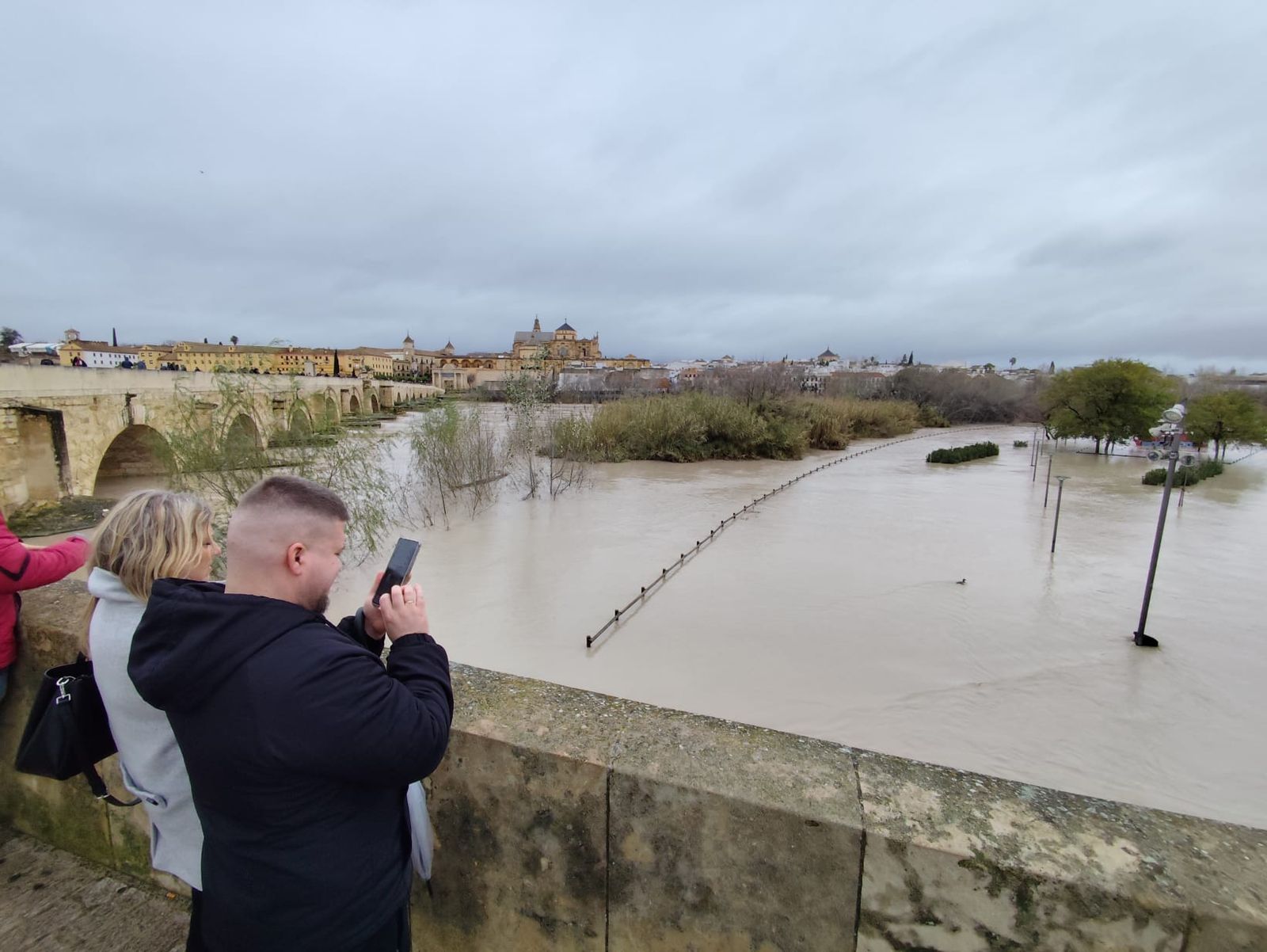 Numerosas personas hacen fotogradías del Guadalquivir a su paso por Córdoba.