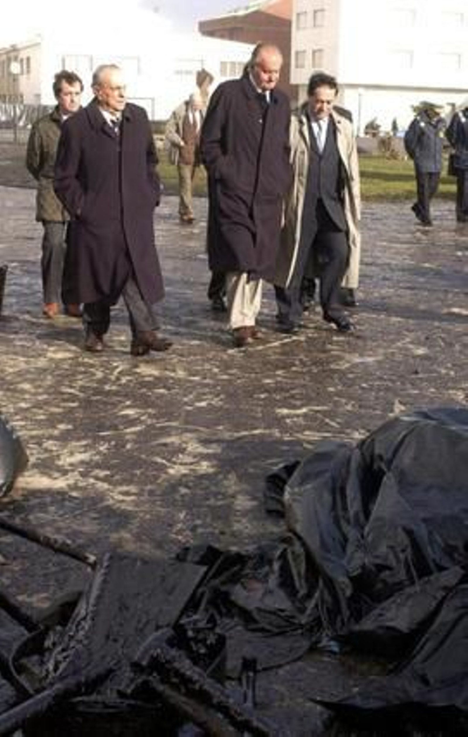 Fraga acompaña al rey Juan Carlos a su llegada al municipio coruñés de Muxía en 2002, durante su visita a la costa gallega afectada por el vertido del petrolero 'Prestige' . / EFE