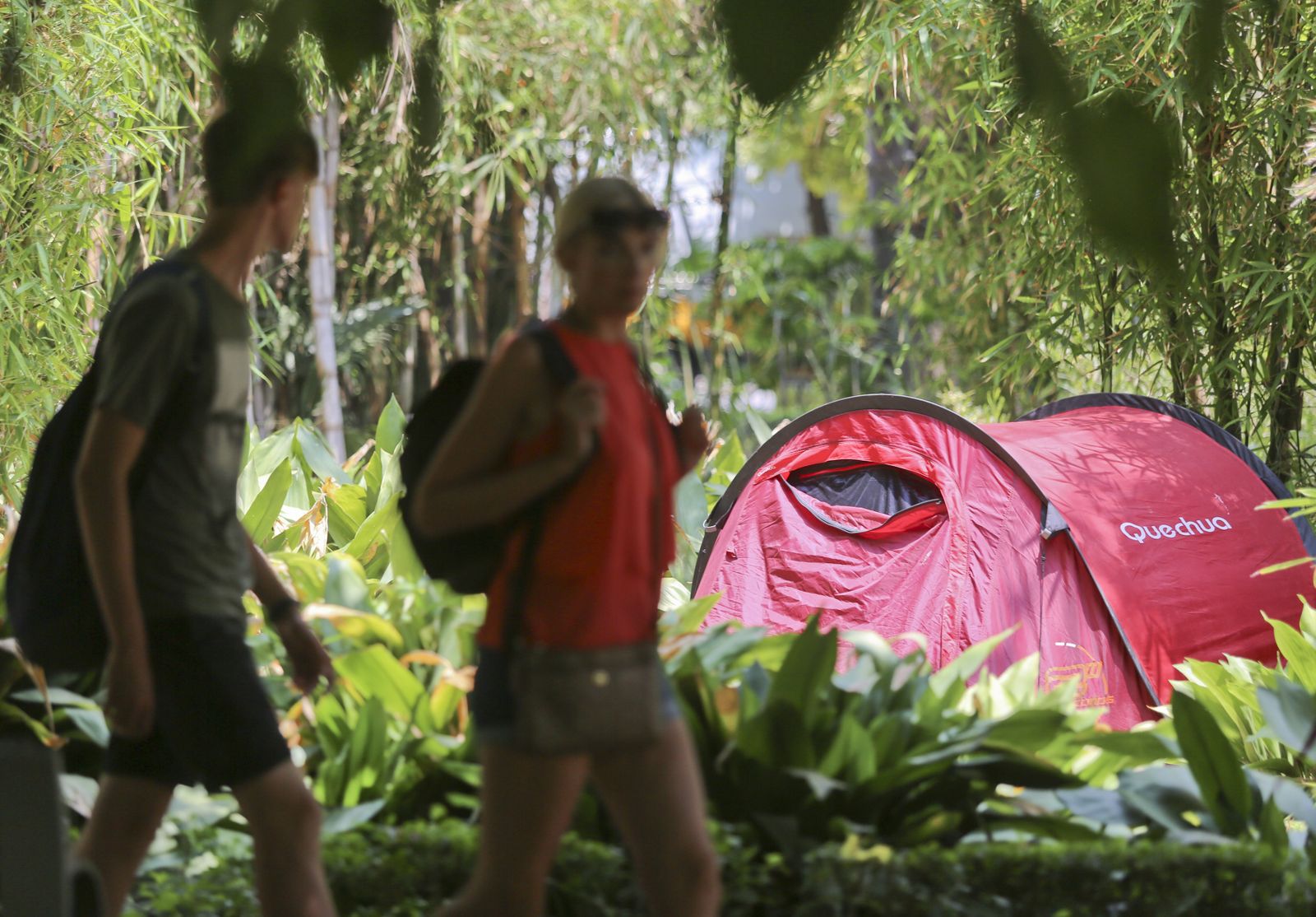 Dos turistas pasean junto a una tienda de campaña