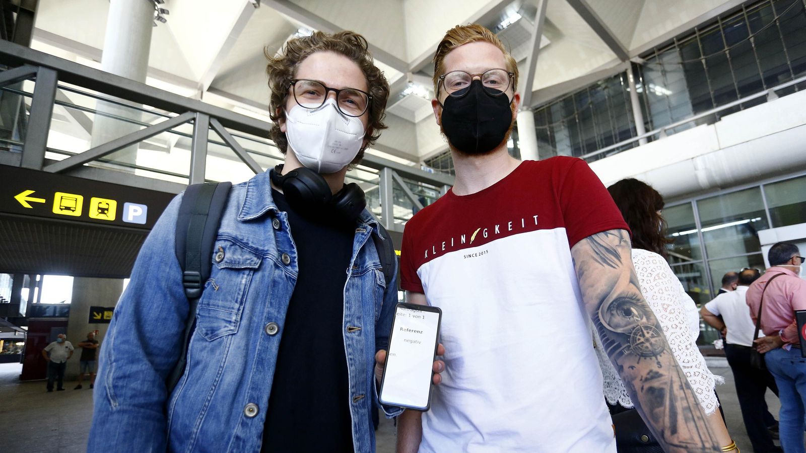 Jan (der.) muestra el código QR de su PCRnegativa. A su lado, Konstantin.