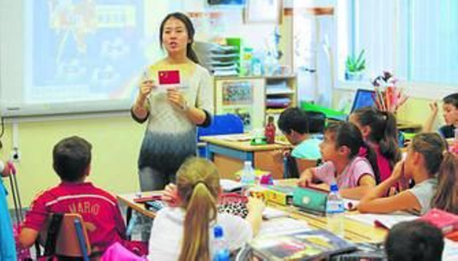La profesora Yuán Zhou, con la bandera de China en sus manos, explica la lección a sus alumnos del CEIP Algazara.