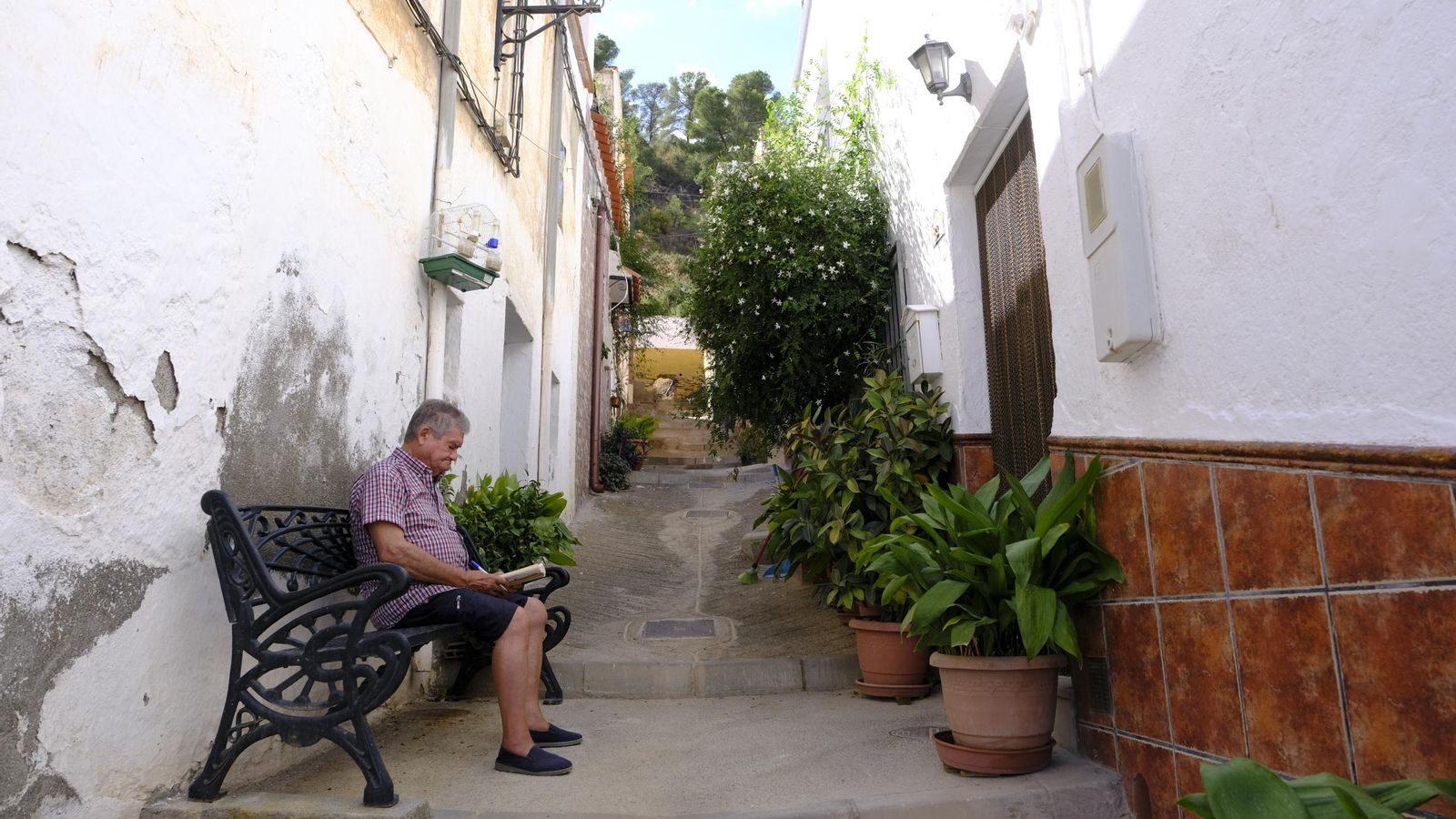 Un vecino de Rágol lee un libro sentado en una las típicas calles empinadas propias de esta localidad de la Alpujarra Almeriense.