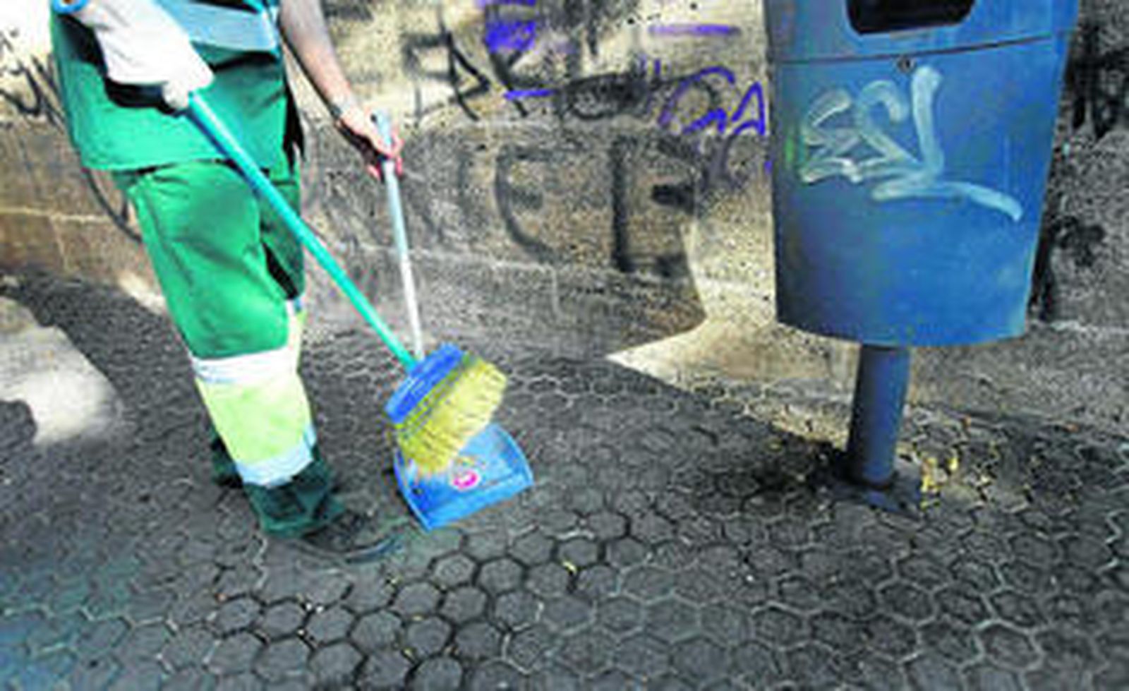 Un barrendero recoge  residuos en la plaza del Castillo. Bajo la papelera, una gran marcha de mugre.