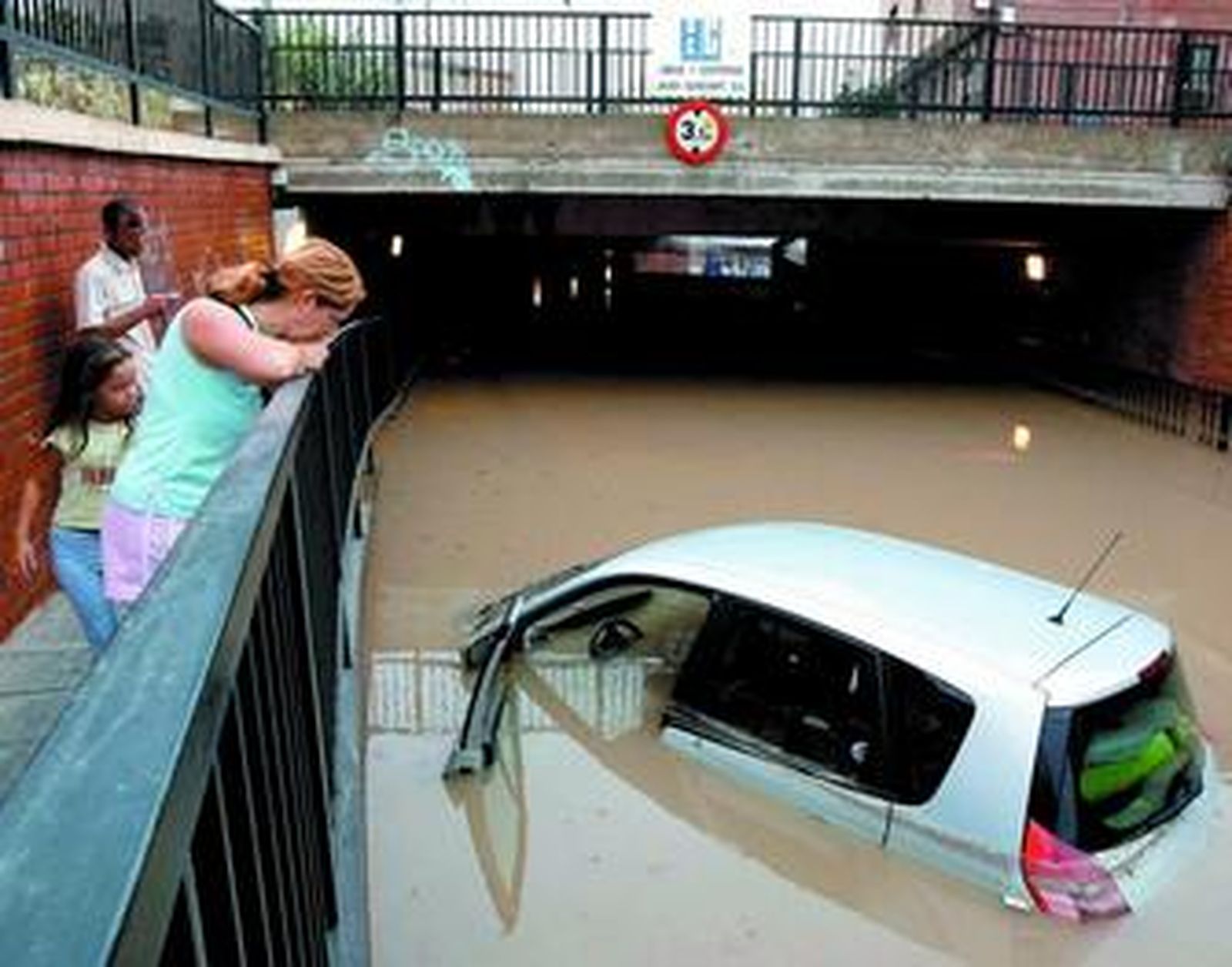 Una mujer contempla un vehículo completamente inundado en una de las zonas más conflictivas, el puente de La Goleta.