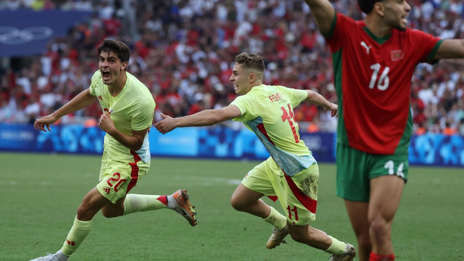Juanlu corre a celebrar su gol agarrando el escudo de España y seguido por Fermín.