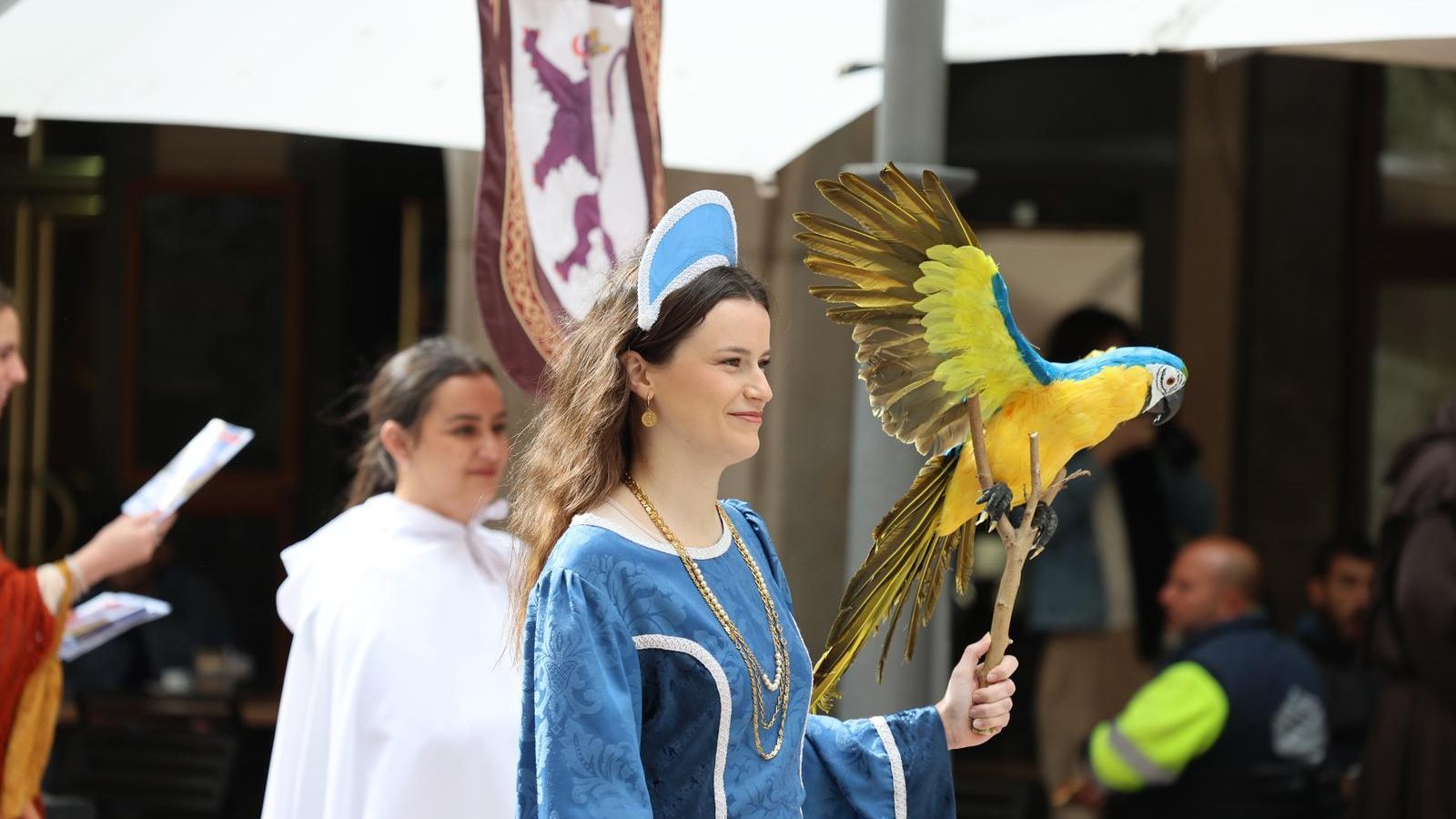 Una de las mujeres de la comitiva caracterizada de época llevando un loro de juguete.