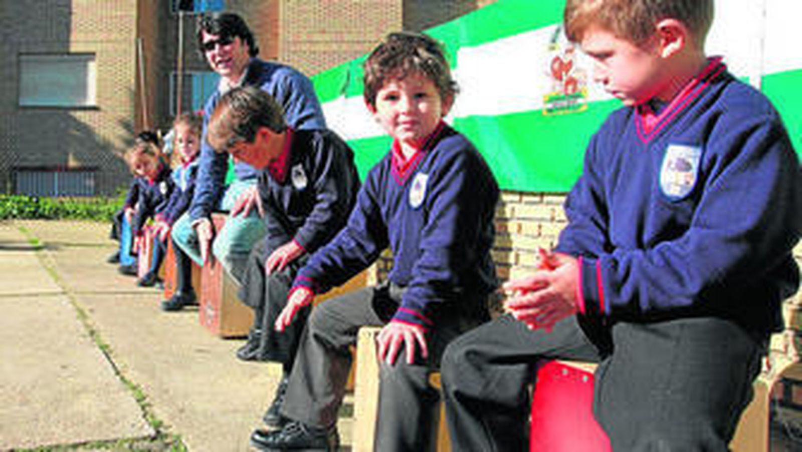 Un grupo de niños aprenden a tocar un cajón flamenco.