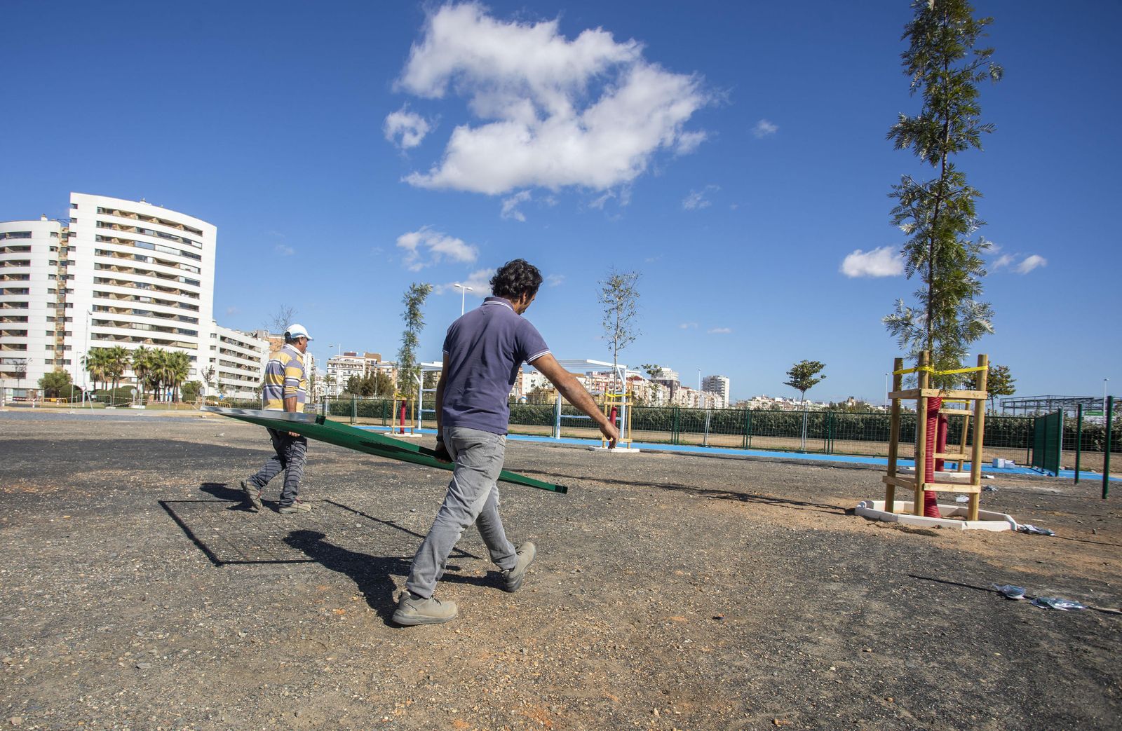 Dos operarios ultiman el área canina del barrio onubense de Pescadería.
