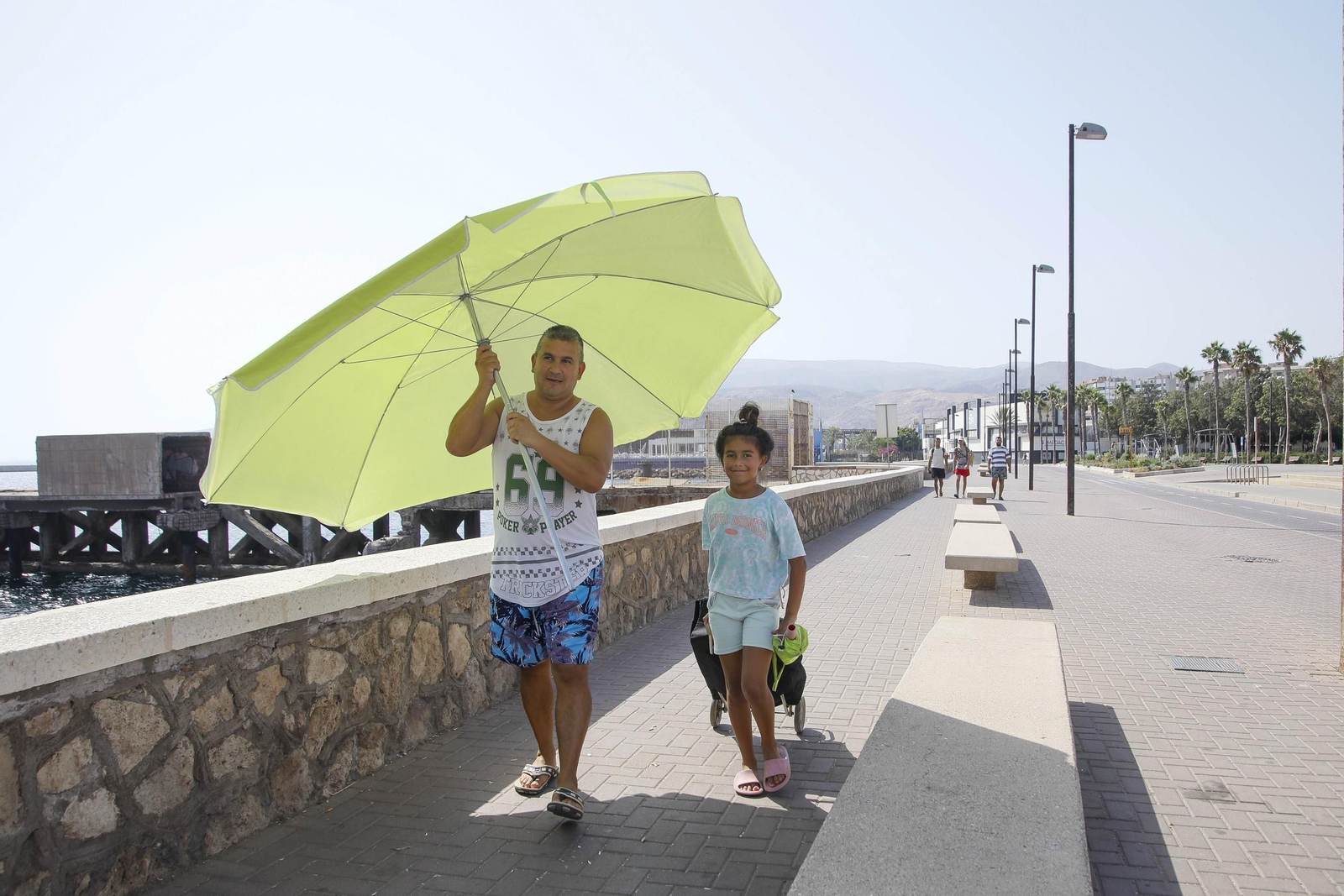 Dos personas se 'esconden' del sol para evitar más calor en el Paseo Marítimo de Almería.