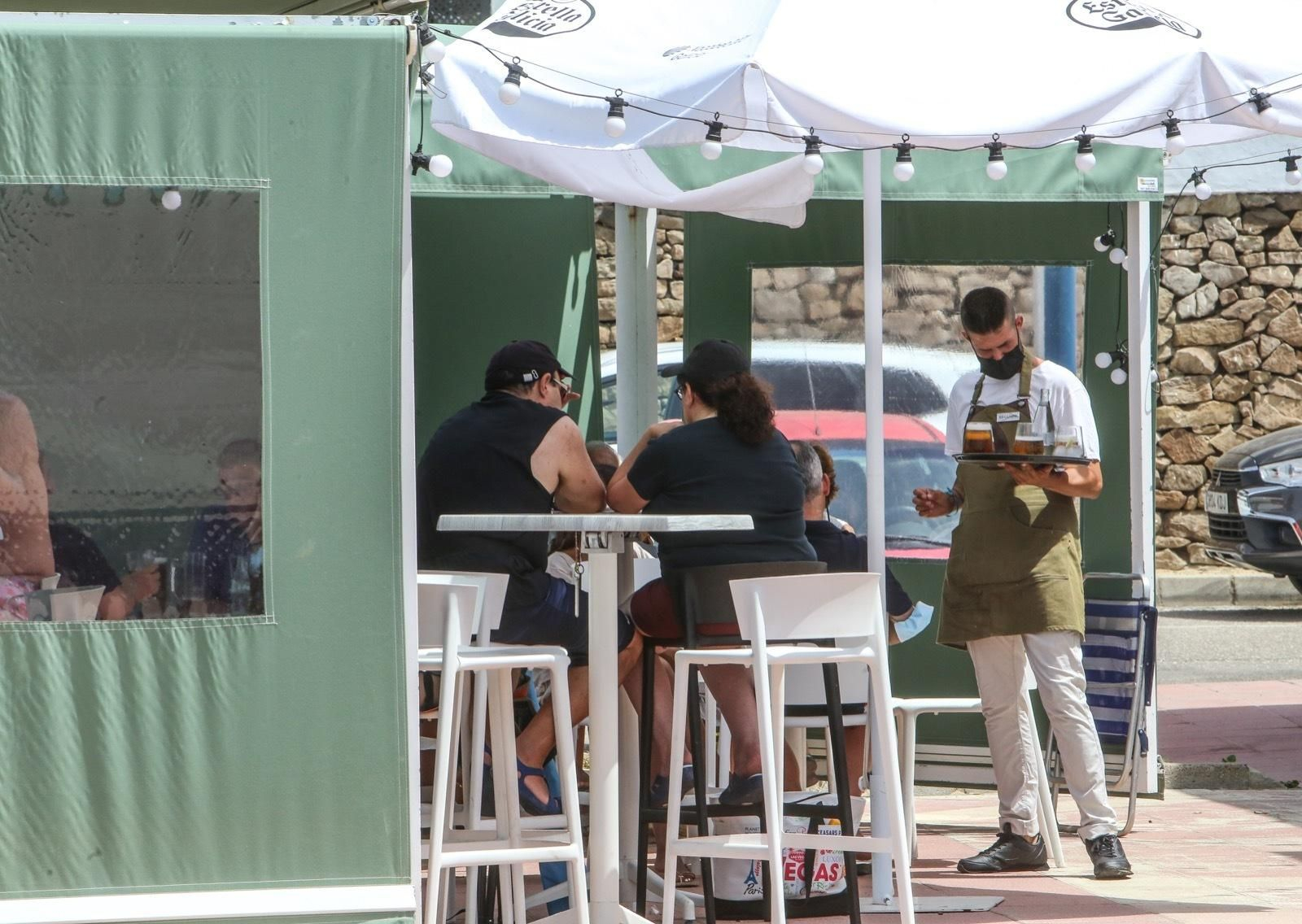 Un camarero sirve a una mesa en un establecimiento de hostelería, este verano en La Barrosa.