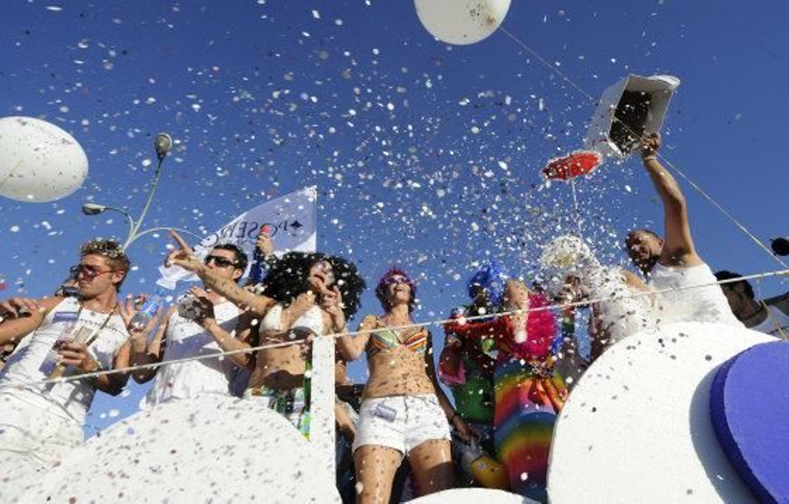 Integrantes de la marcha tiran confeti desde una carroza.