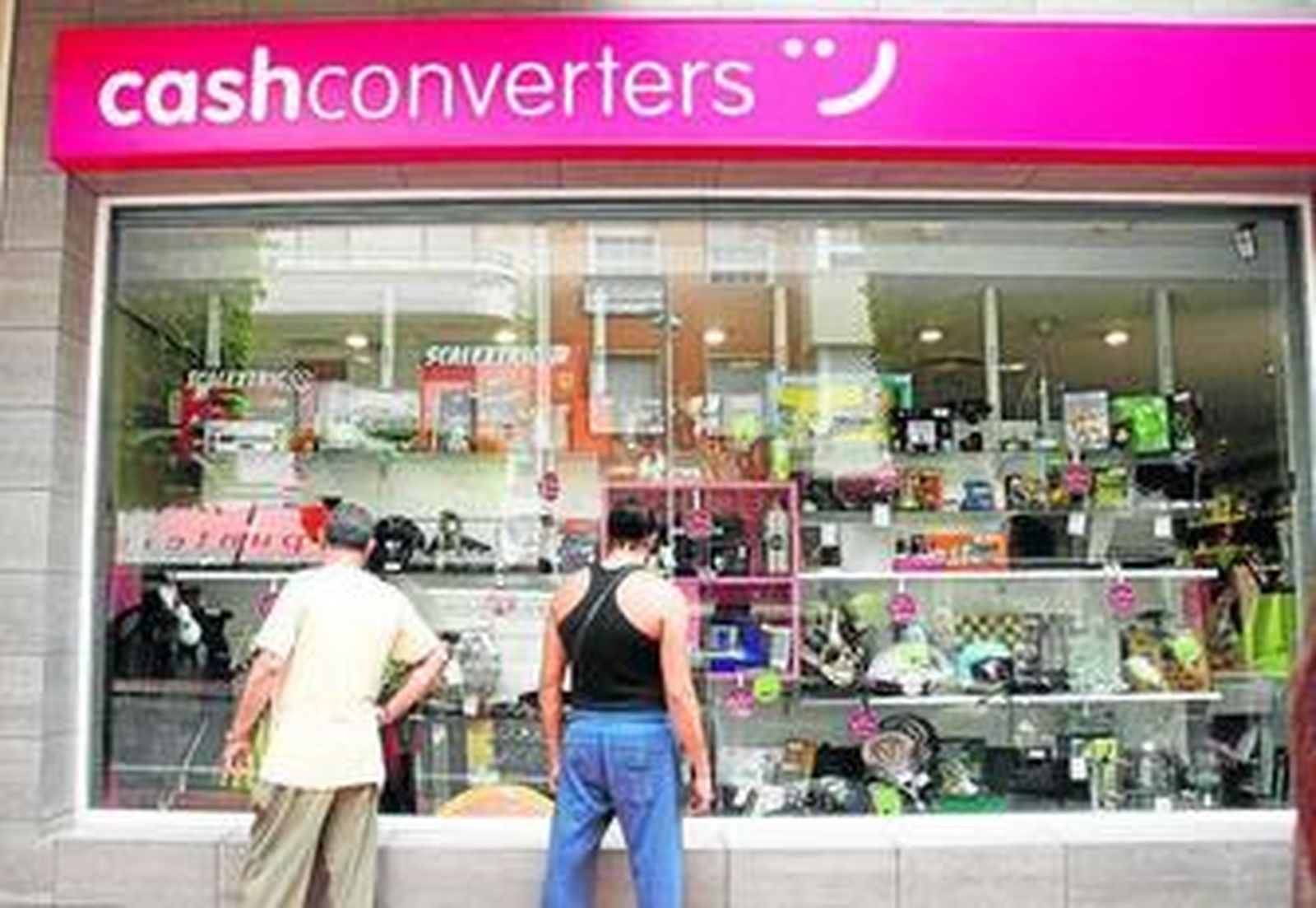 Dos ciudadanos observan el escaparate del establecimiento comercial en la Avenida de la Estación.