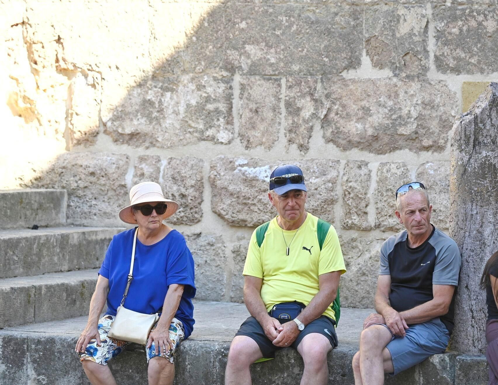 Unos turistas se toman un descanso en uno de los muros de la Mezquita-Catedral de Córdoba.