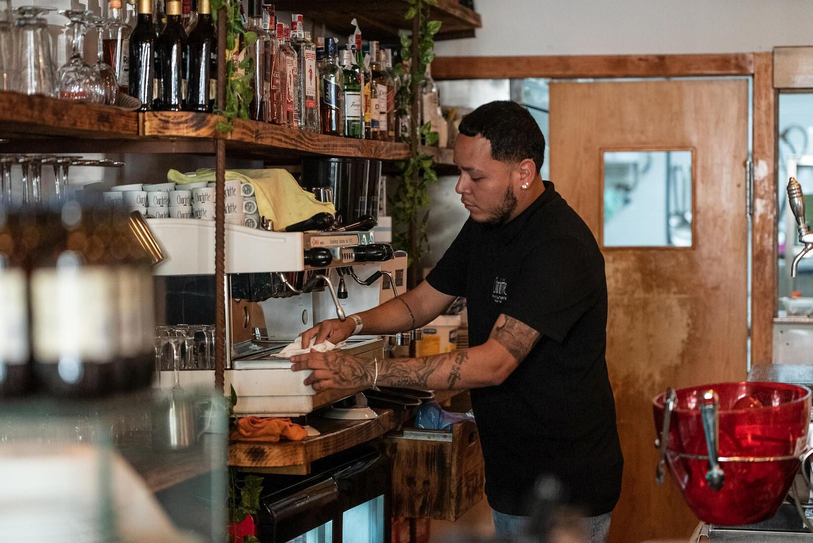 Un camarero limpia una cafetera en un local de hostelería
