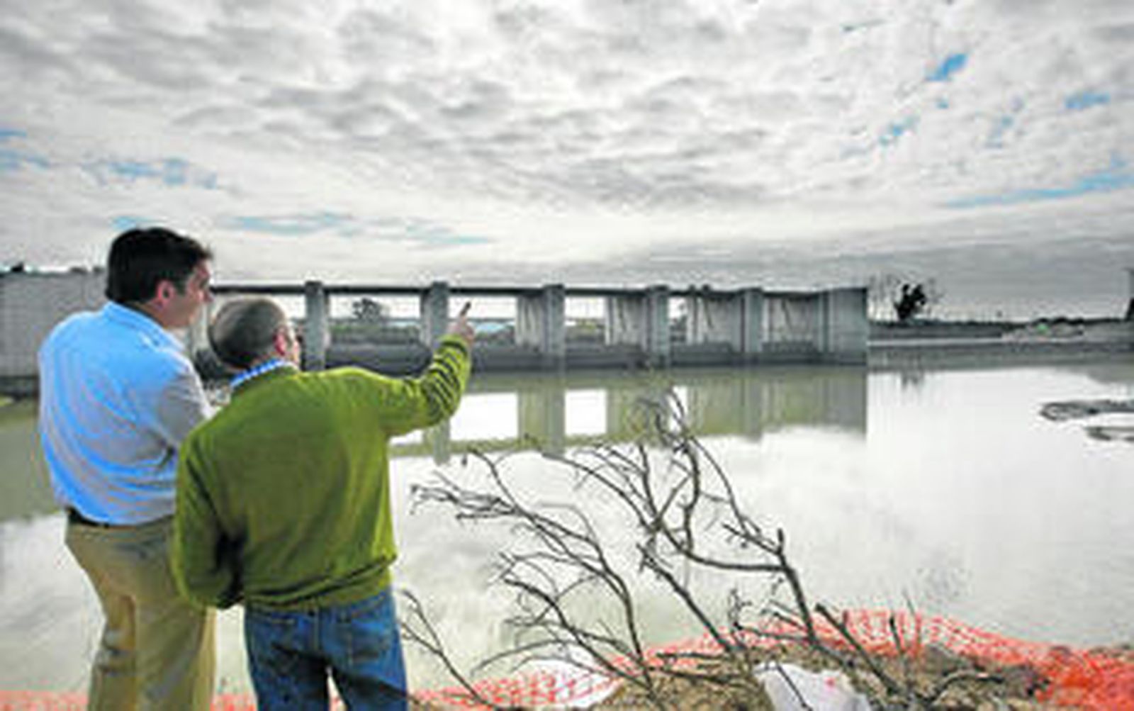El jefe y el director de obra de la empresa Sarrión y Cyopsa, Luis López y Luis García, respectivamente, miran el azud móvil desde la margen provisional del río.