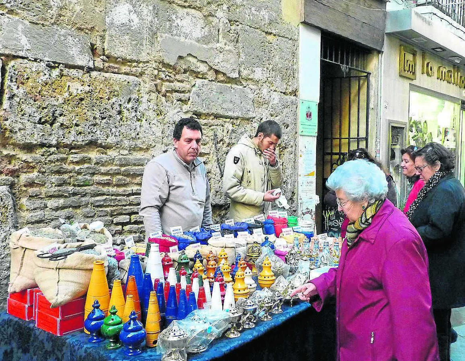 Varias mujeres observan incensarios en un puesto callejero.