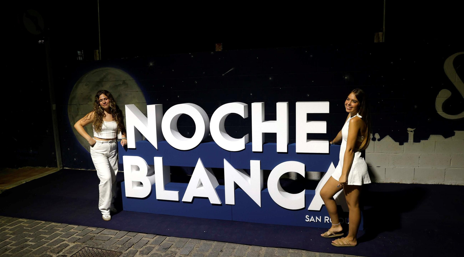Dos chicas junto al cartel de la Noche Blanca, el pasado año.