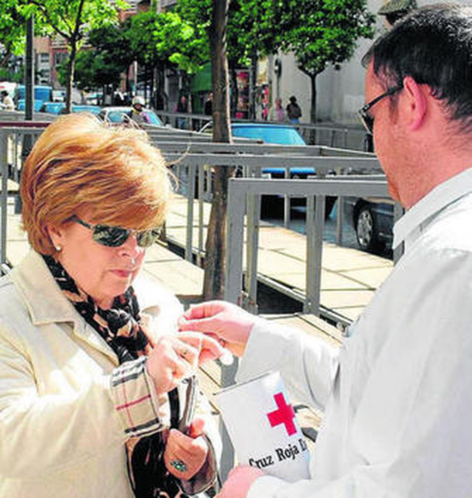Una ciudadana aporta un donativo en una de las huchas de Cruz Roja.