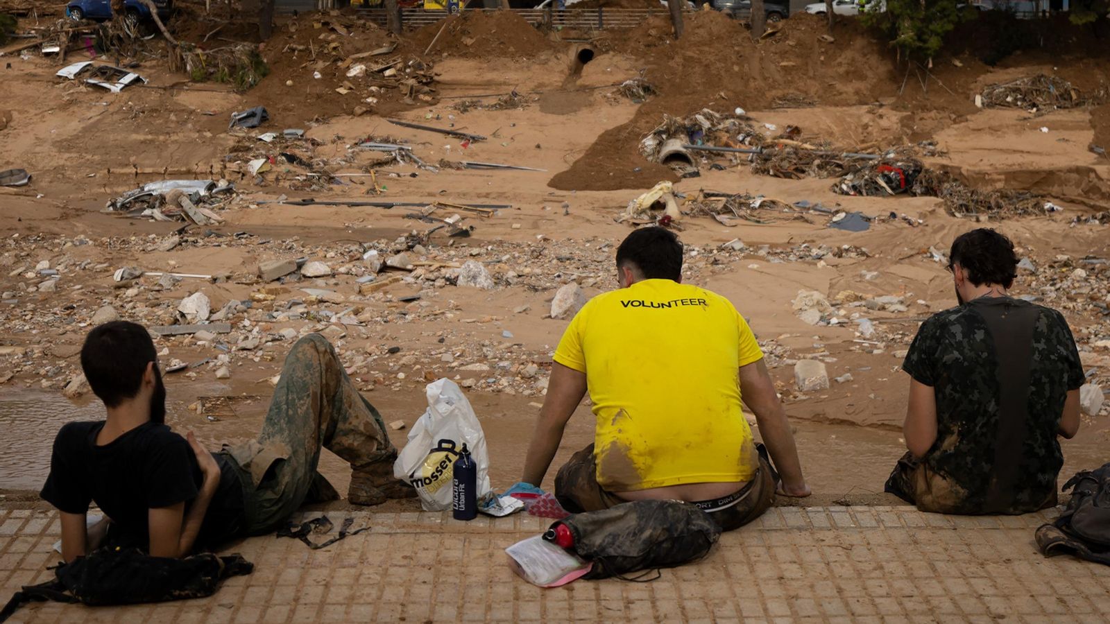 Voluntarios descansan ante el barranco del Poyo, en Paiporta