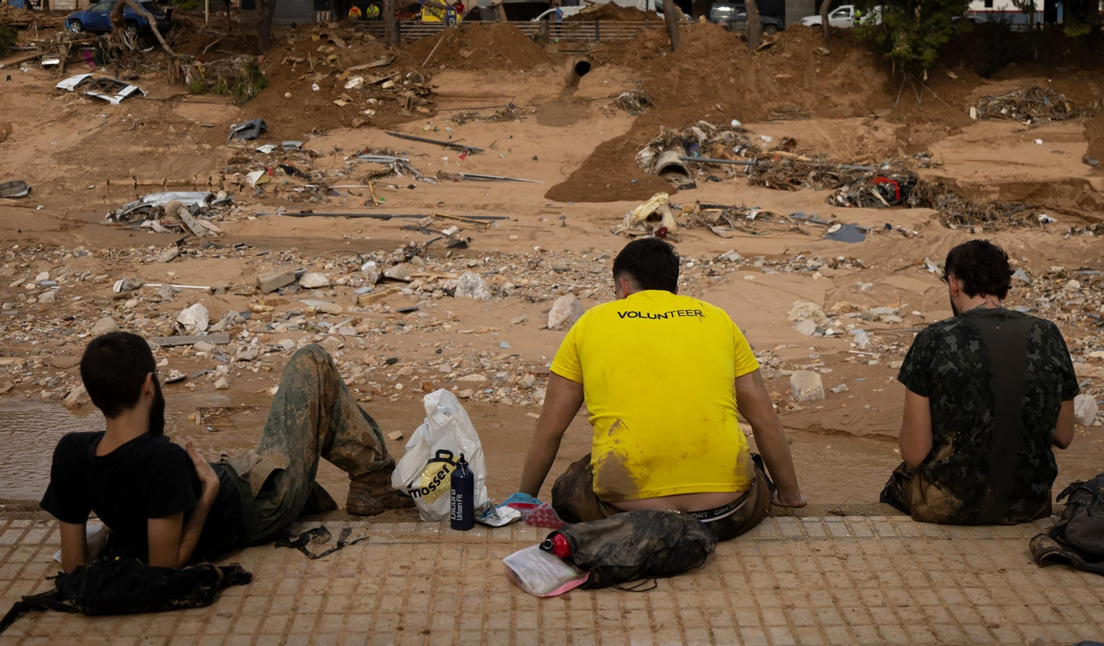 Voluntarios descansan ante el barranco del Poyo, en Paiporta.
