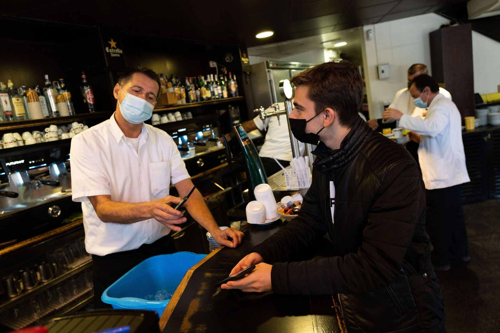 El responsable de un bar en Cataluña comprueba la validez del pasaporte Covid de un cliente.