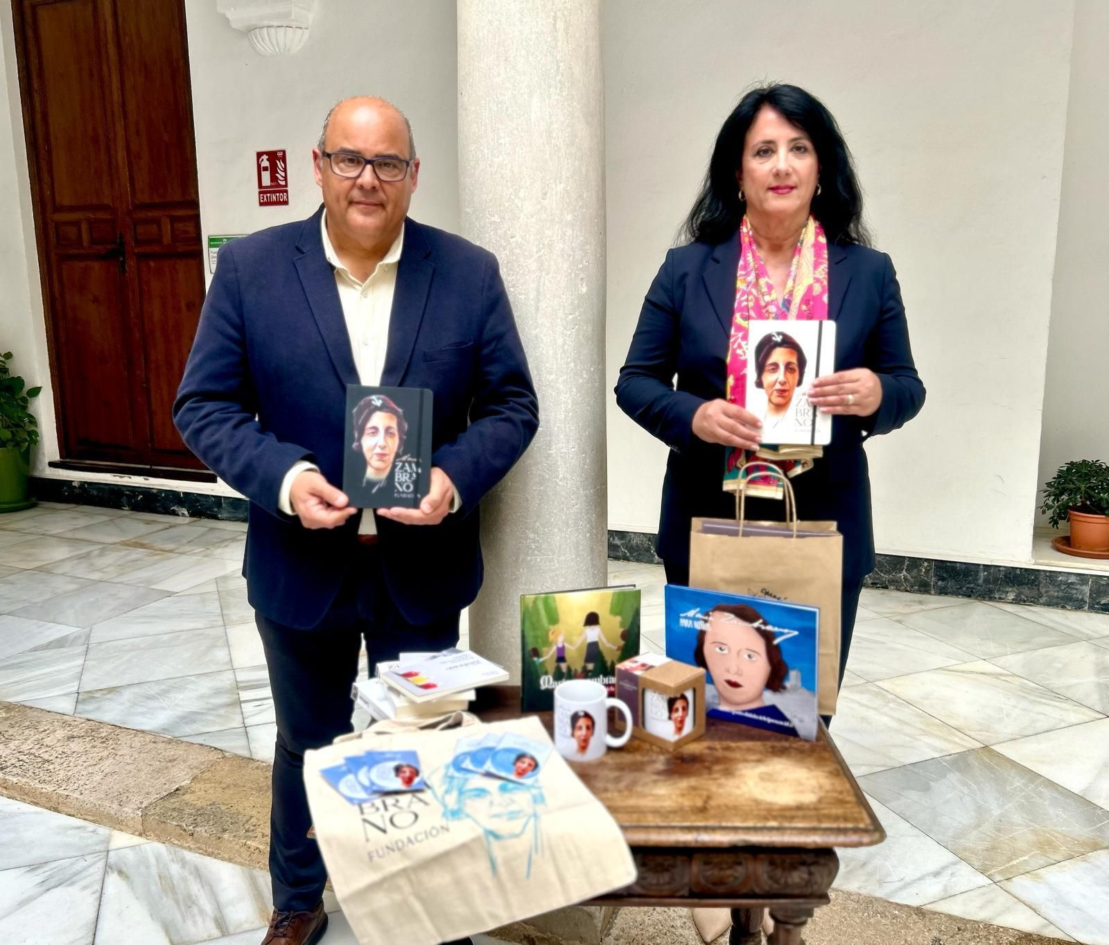 El alcalde del municipio, Jesús Lupiáñez, y Alicia Ramírez, concejala de Cultura, mostrando algunos de los productos de merchandising de María Zambrano
