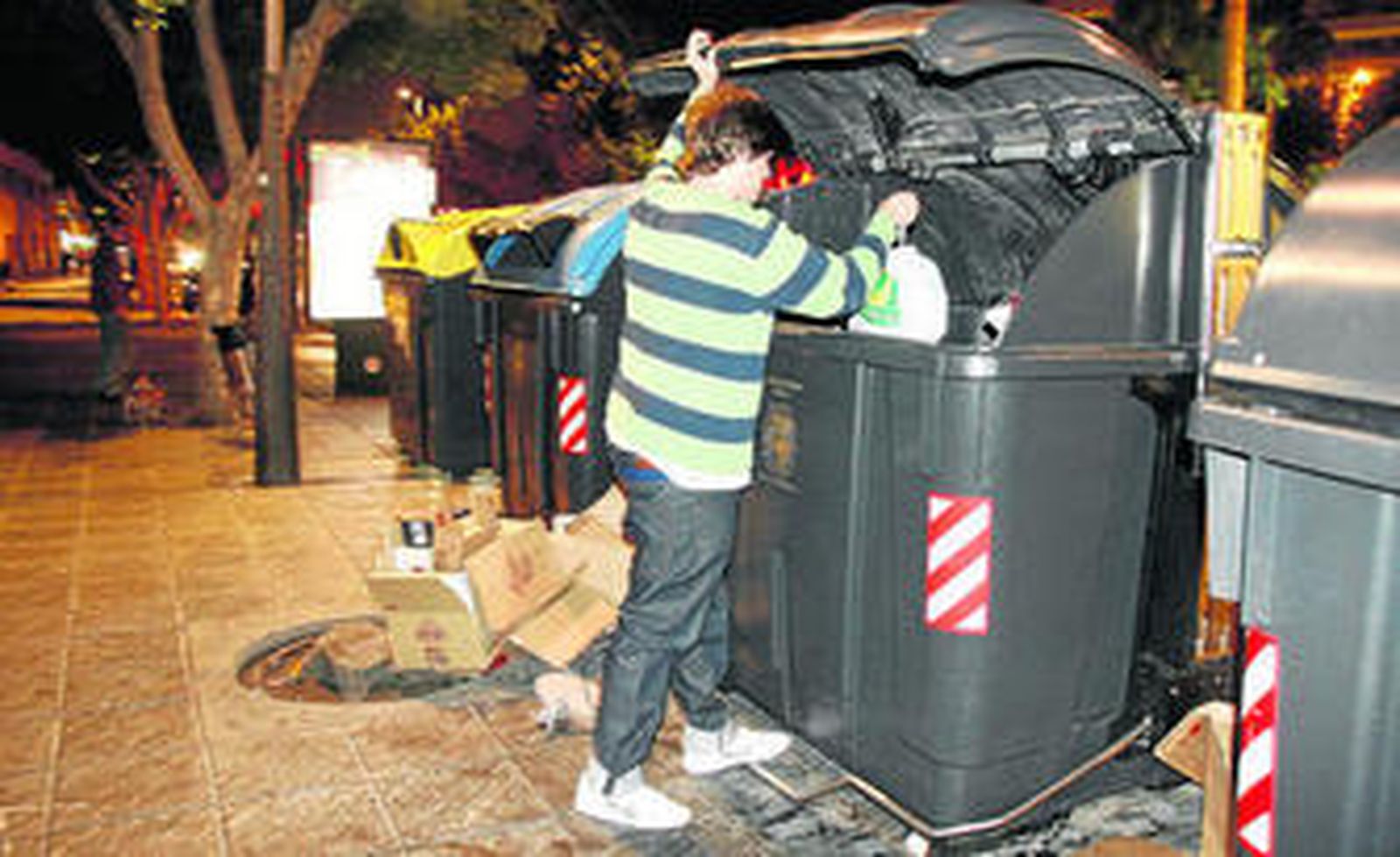 Un joven busca en los contenedores de basura de Almería restos de la comida que tiran los supermercados.