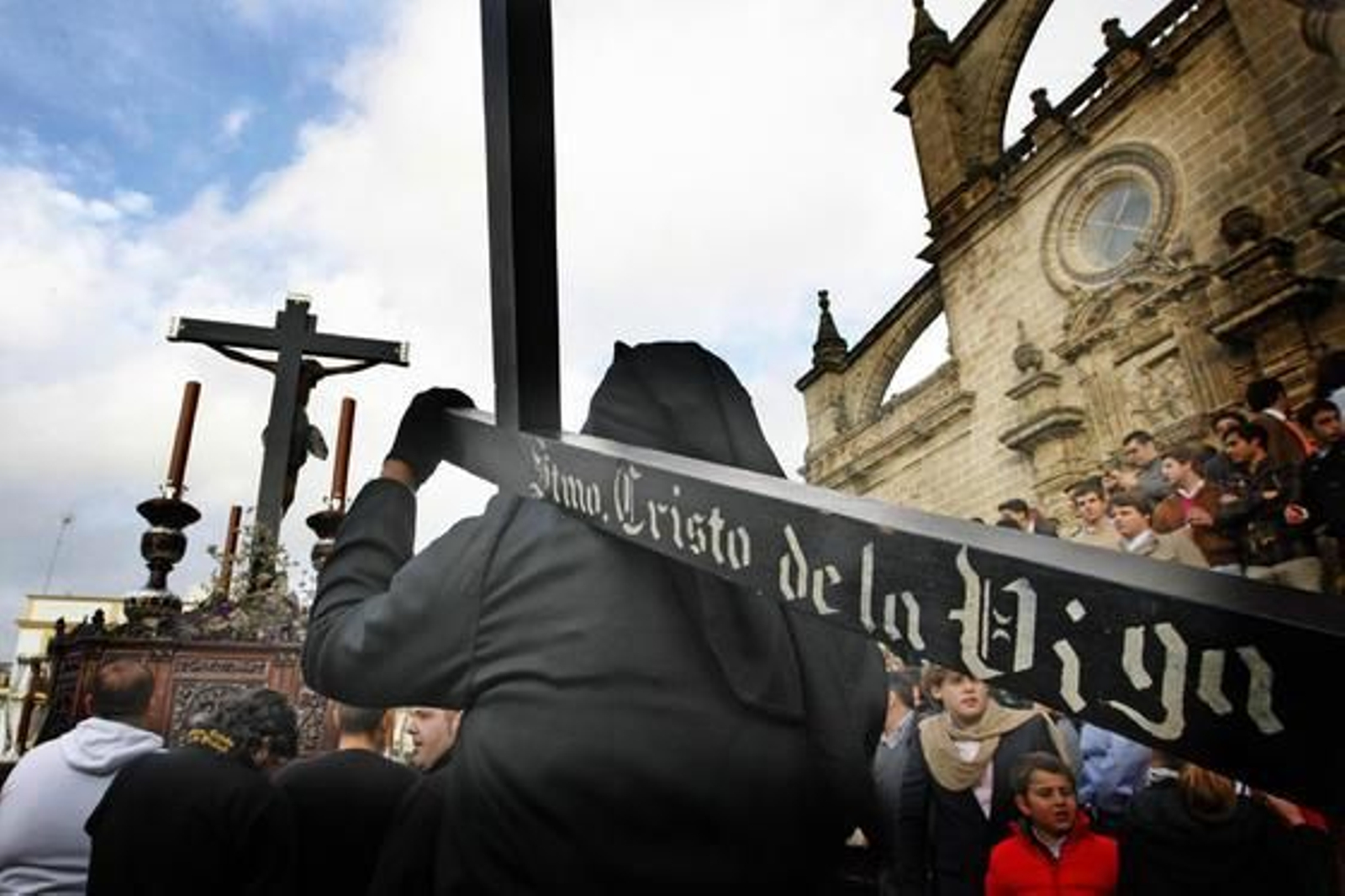Un nazareno de la Hermandad de La Viga hace penitencia con la cruz tras el misterio del Santísimo Cristo, que baja por el reducto de la la Santa Iglesia Catedral.

Foto: Pascual