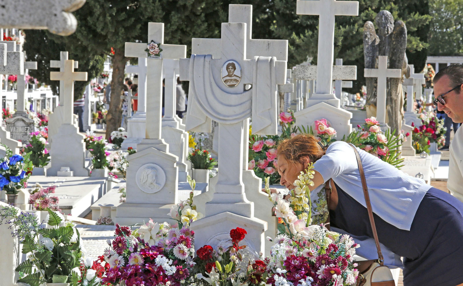Una pareja, junto a un nicho en el cementerio.