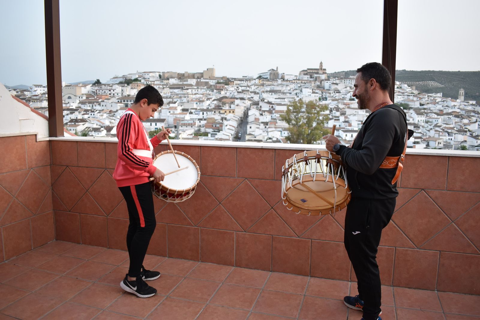 Dos baenenses tocan el tambor en una terraza.