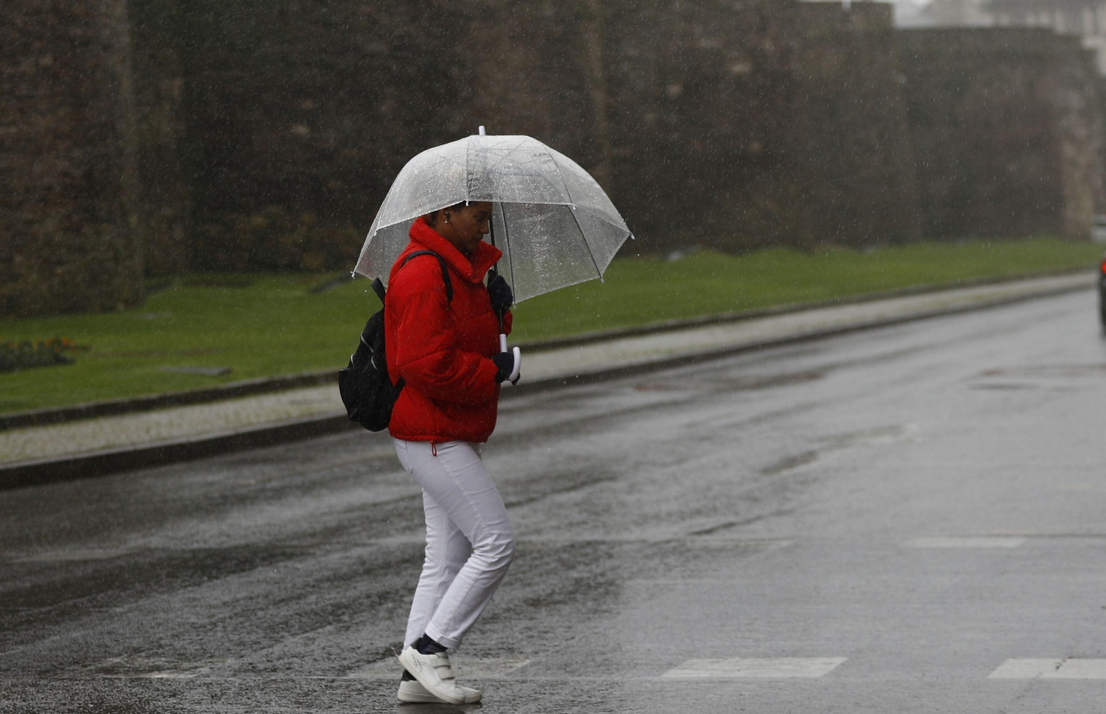 Una mujer se protege de la lluvia con un paraguas.