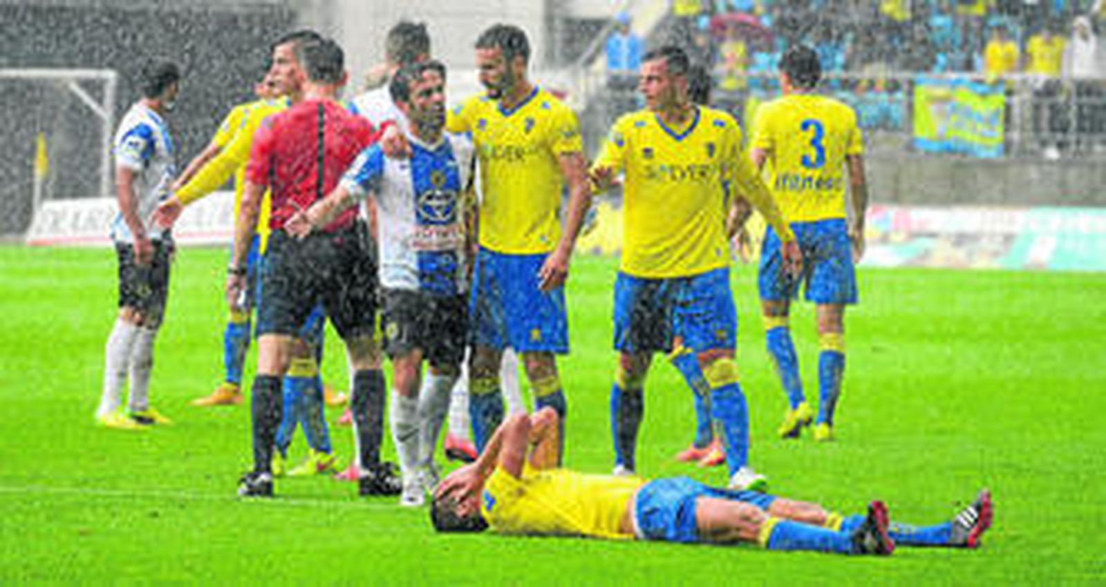 Garrido espera sobre el césped a ser atendido por el equipo médico mientras a su lado se encuentran jugadores del Cádiz y el Hércules.