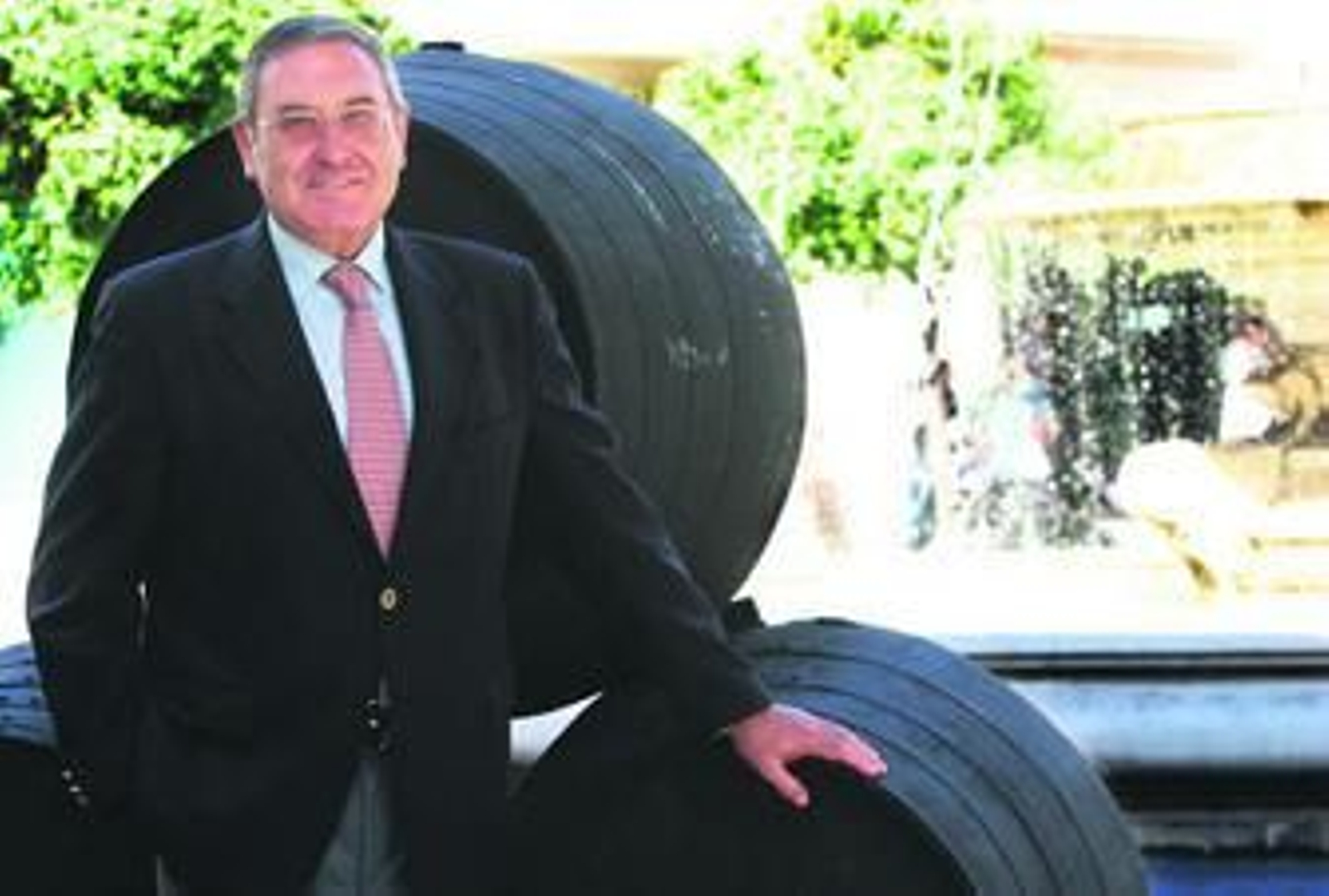 El ex presidente del vino posa junto a una andana de botas con gesto sonriente.