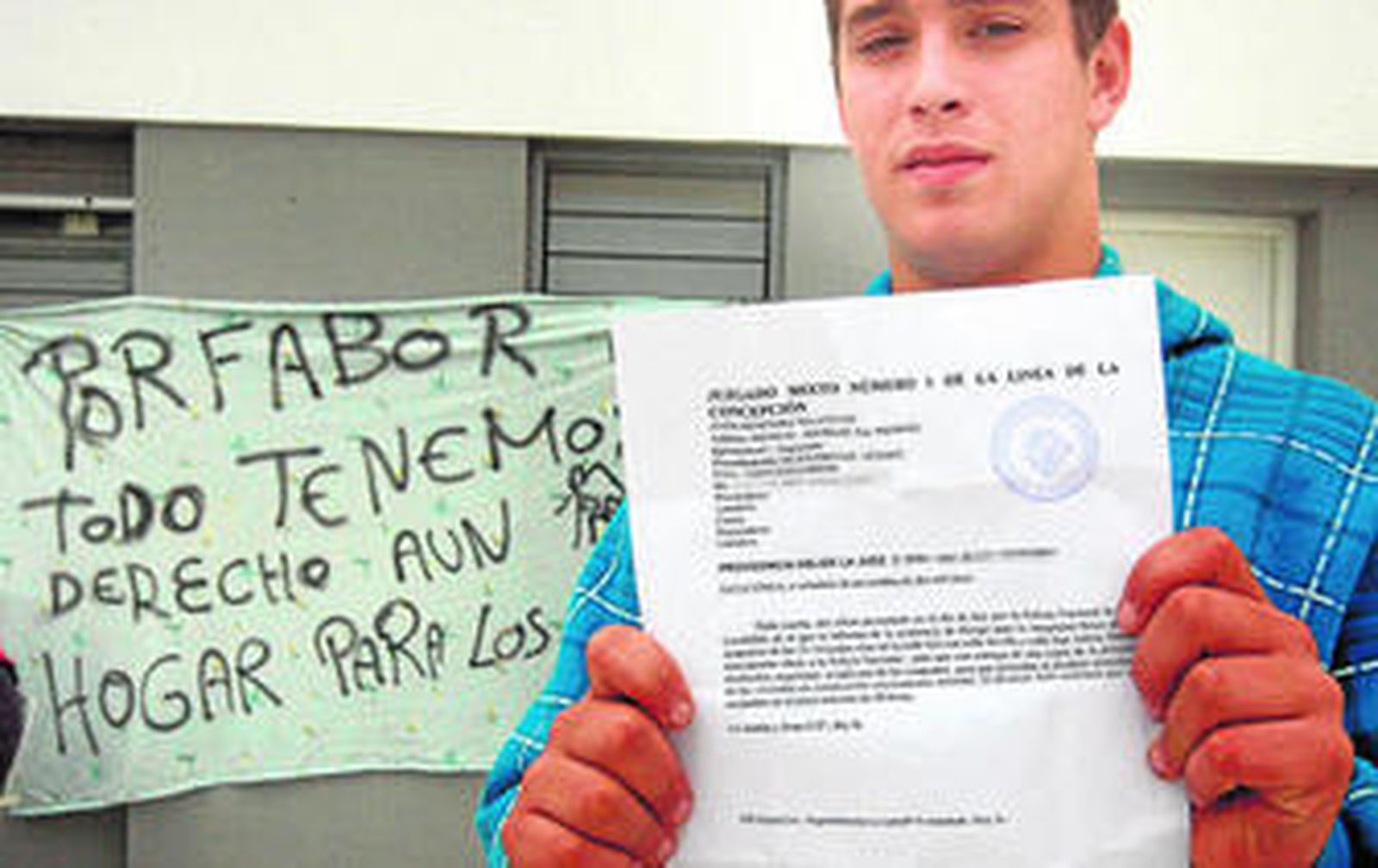 Un joven enseña la orden judicial de desalojo emitida por la juez del número 1 el viernes.