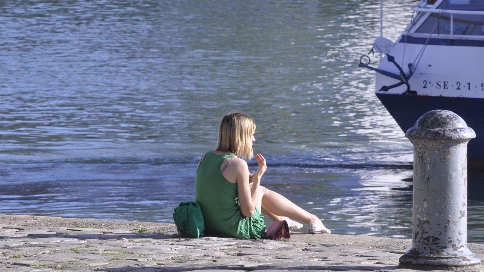 Una joven disfruta del sol junto al río.