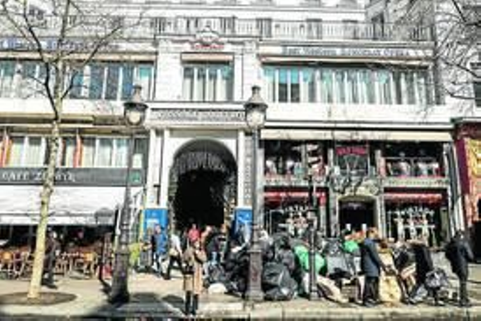 Varias personas caminan cerca de montones de basura en París.